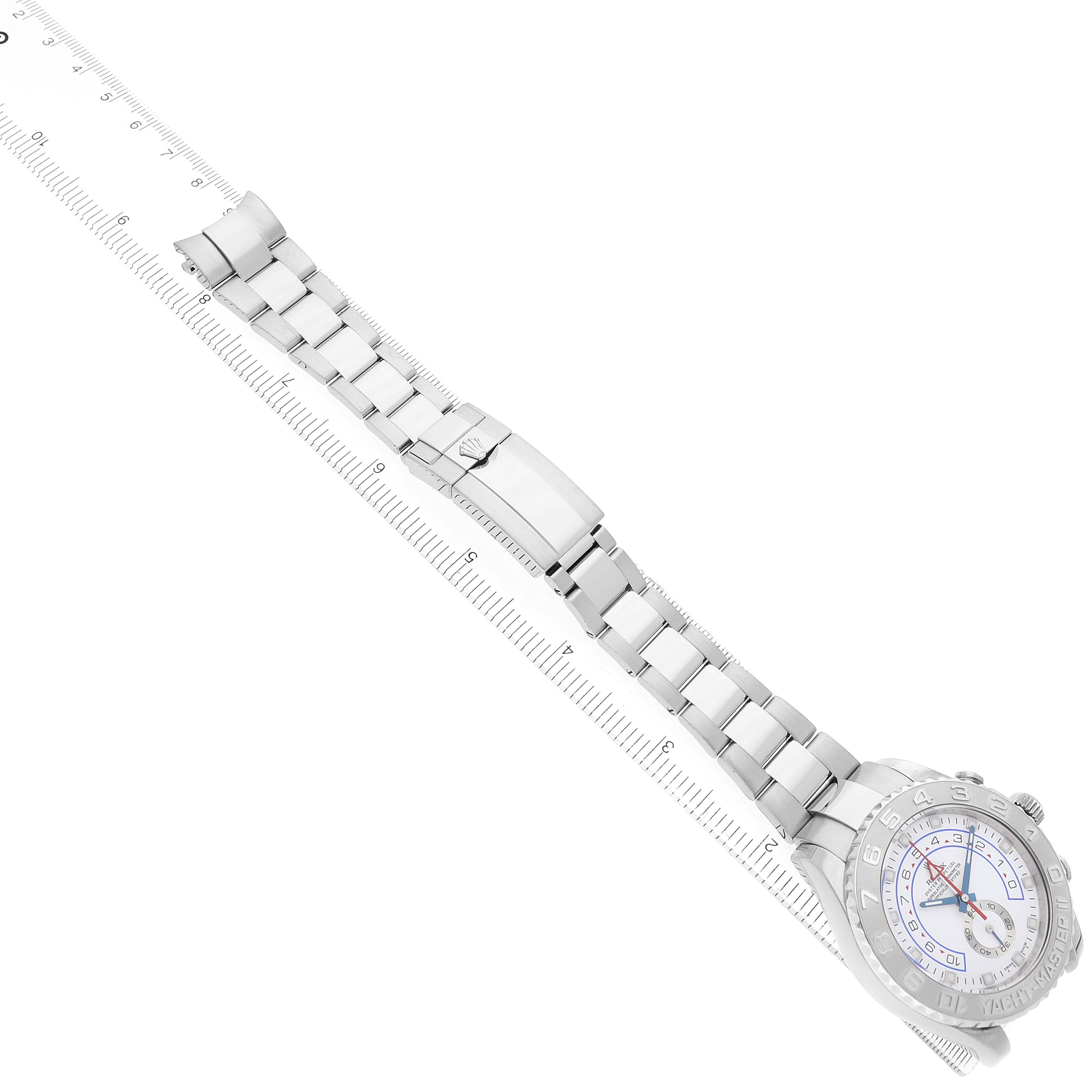 The Rolex Yacht-Master 116689 Men's White Gold White Dial watch is shown at an oblique angle, highlighting the bracelet, clasp, and face against a ruler.