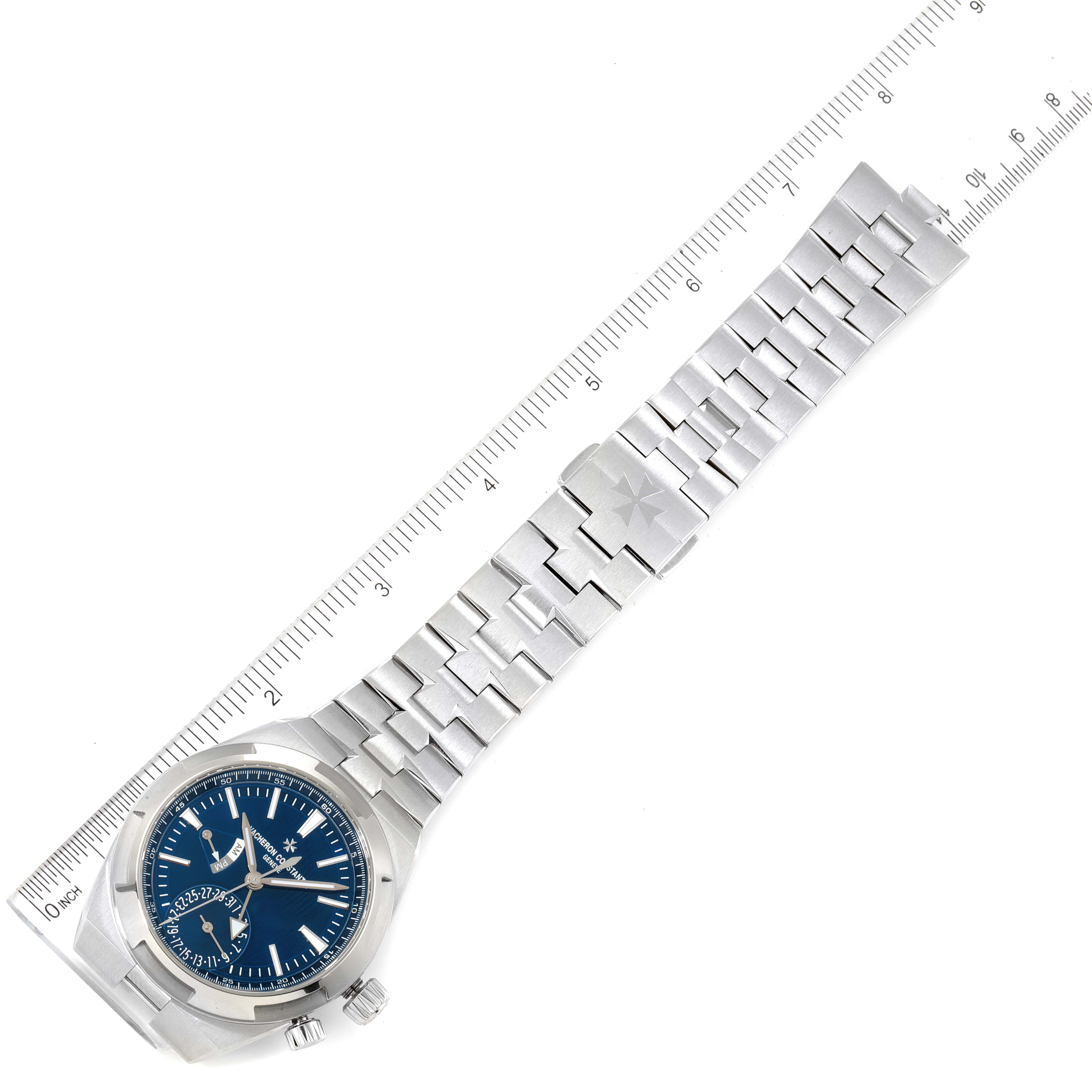 The image shows the Vacheron Constantin Overseas 7900V/110A-B334 Men's Stainless Steel Blue Dial 7900V/110A-B334 Men's Stainless Steel Blue Dial watch laid flat, displaying the face, bracelet, clasp, and part of a ruler for scale.