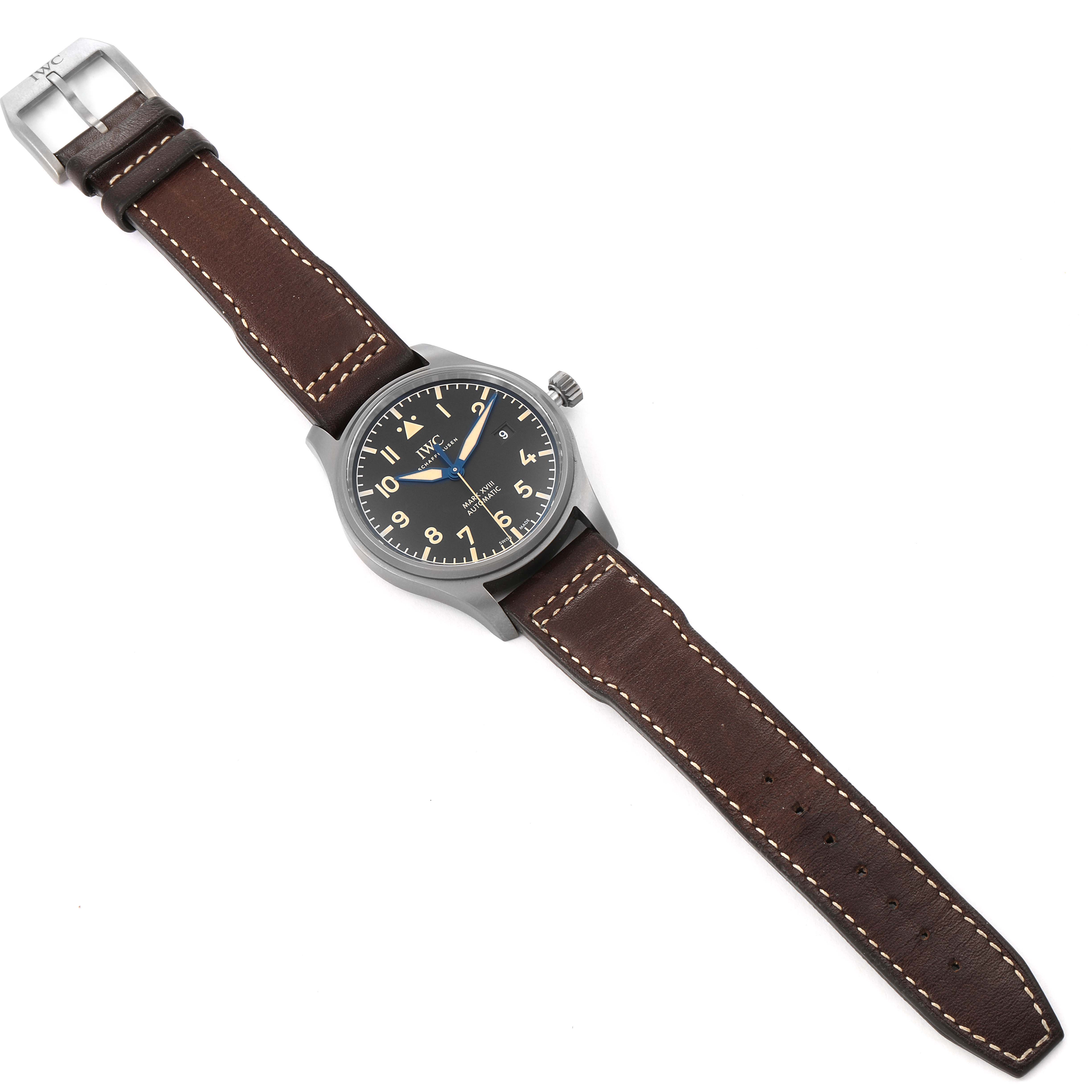 The IWC Pilot IW327006 Men's Titanium Black Dial IW327006 Men's Titanium Black Dial model watch is shown from an overhead angle, displaying its face, brown leather strap, and buckle.