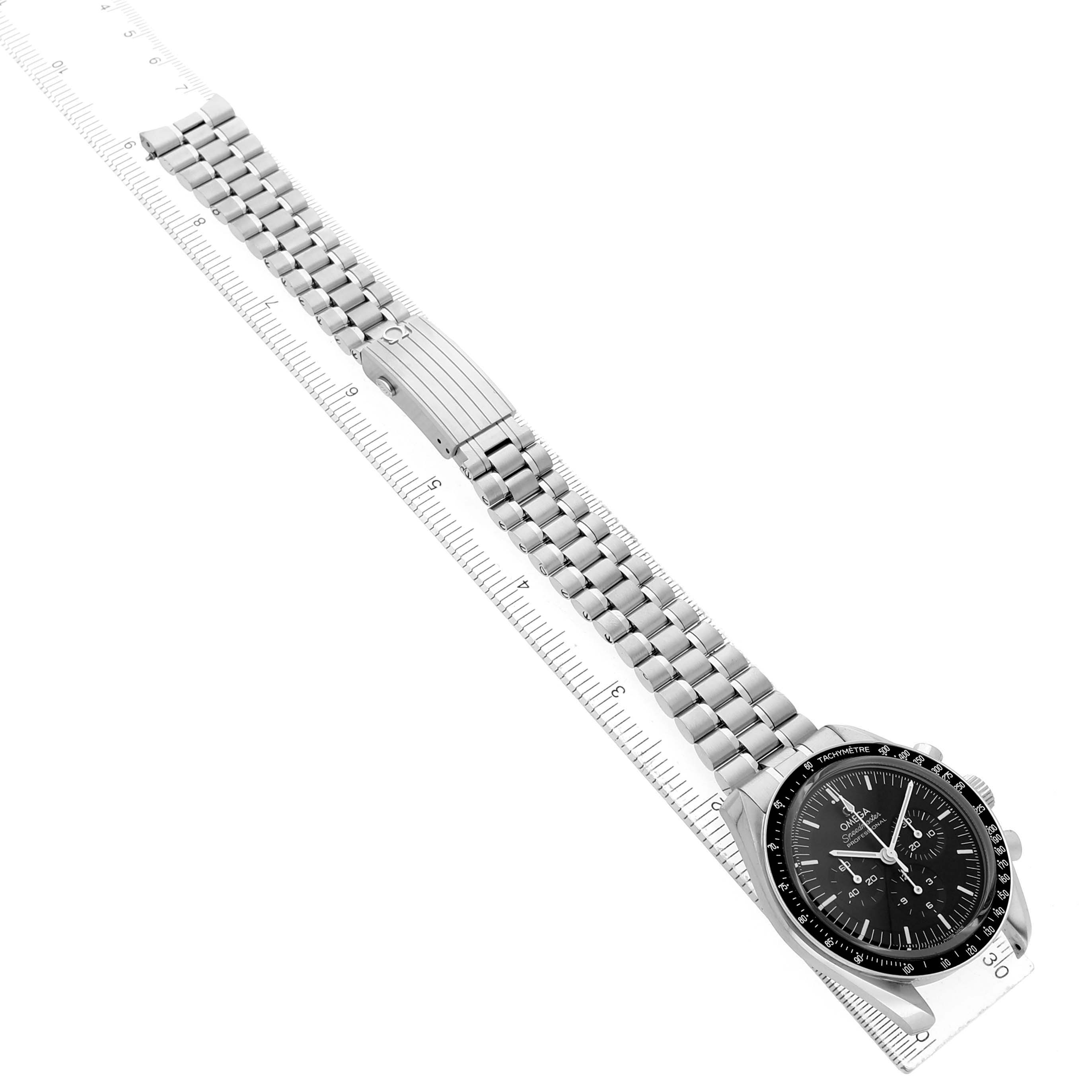 The Omega Speedmaster 310.30.42.50.01.002 Men's Stainless Steel Black Dial watch is shown from an overhead angle, featuring its face and full metal bracelet with clasp on a measuring scale.