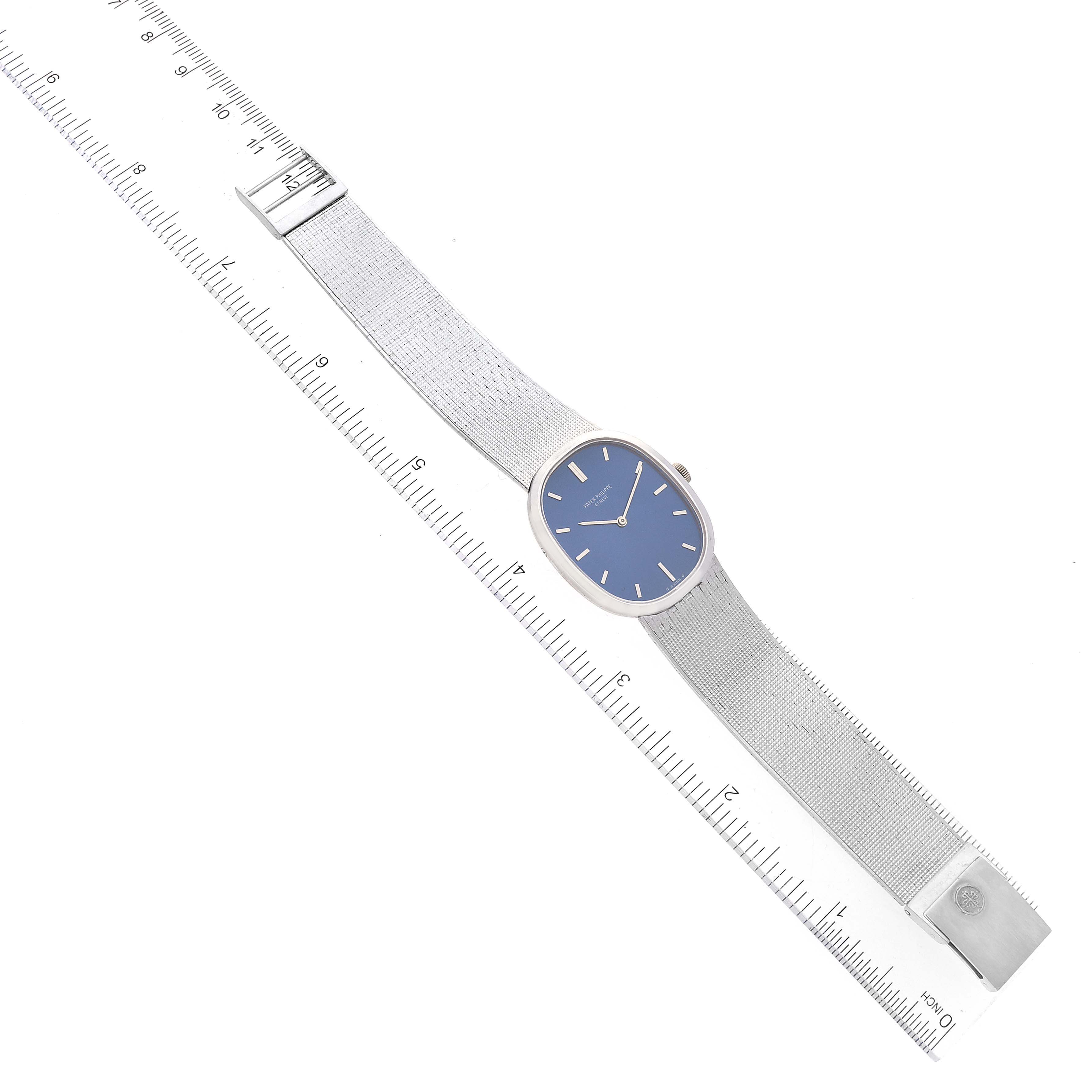 The Patek Philippe Golden Ellipse 3548 Women's White Gold Blue Dial 3548 Women's White Gold Blue Dial watch is shown from a top-down angle, displaying its blue dial, entire strap, and clasp next to a ruler.