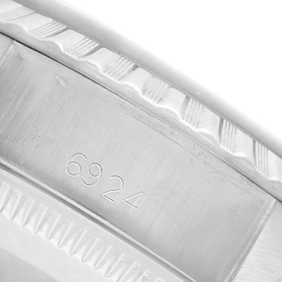 The image shows a close-up of the case edge of a Rolex Date 6924 Women's Stainless Steel Silver Dial 6924 Women's Stainless Steel Silver Dial model, focusing on the serial number and fluted bezel details.