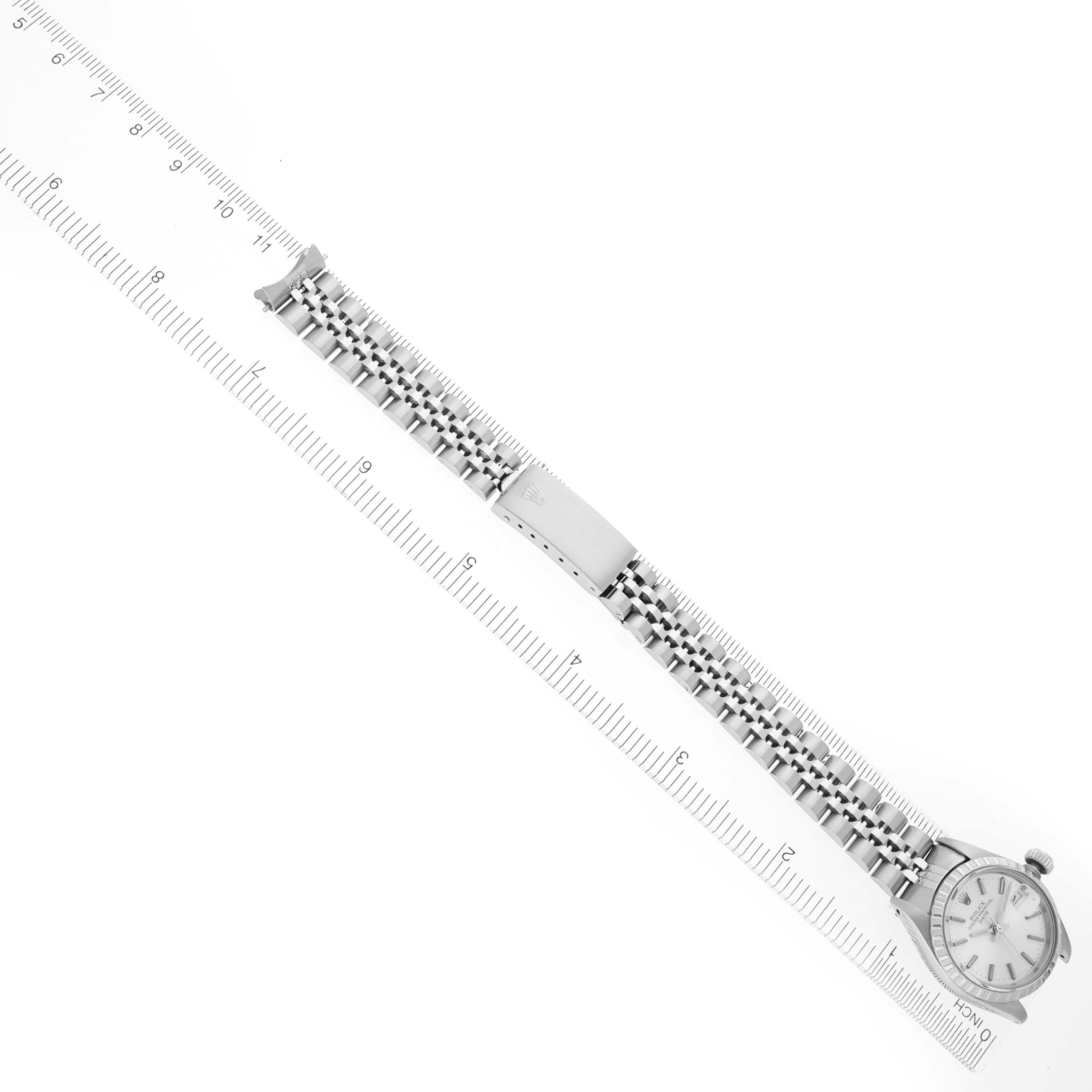 The image shows a Rolex Date 6924 Women's Stainless Steel Silver Dial 6924 Women's Stainless Steel Silver Dial model watch from a top-down angle, displaying the face, bracelet, and clasp alongside a ruler for scale.