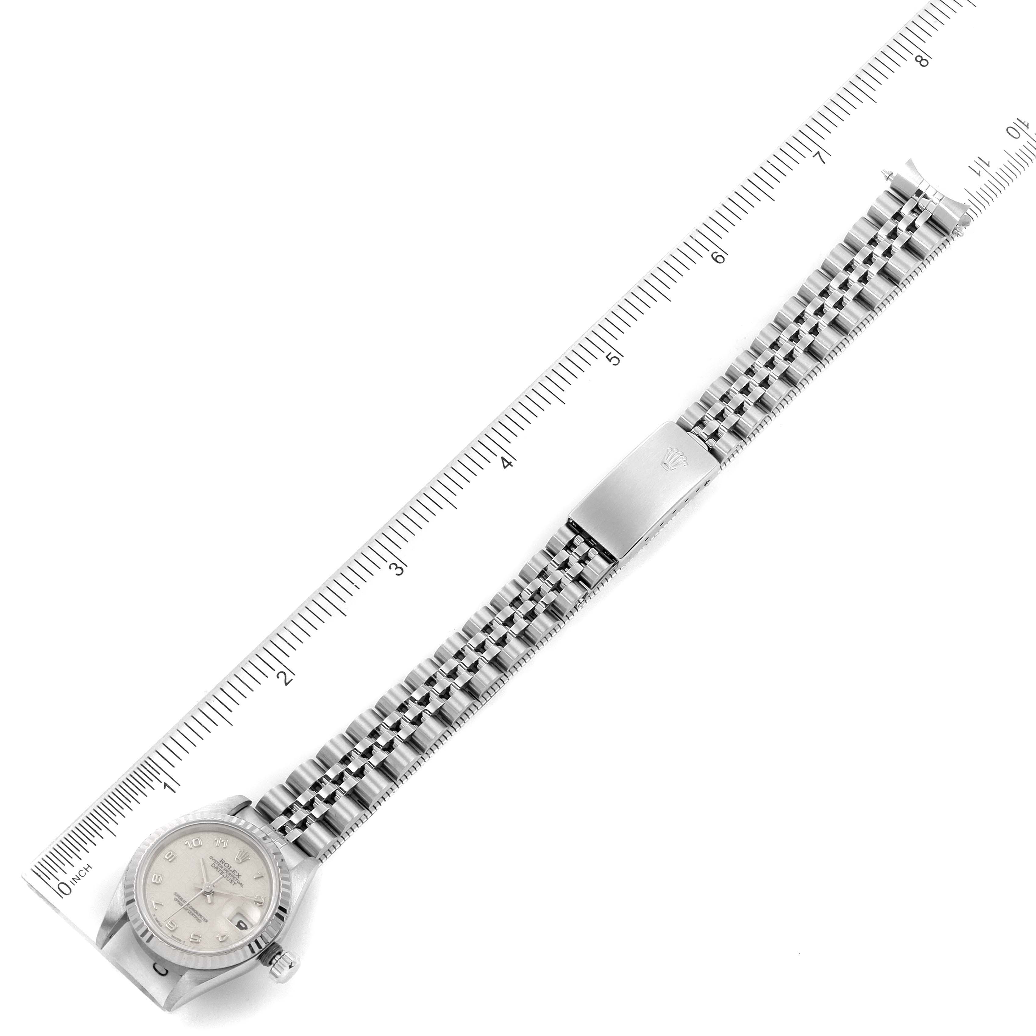 The image shows an overhead view of the Rolex Datejust 69174 Women
s Stainless Steel Silver Dial 69174 Women
s Stainless Steel Silver Dial watch, including the dial, bracelet, and clasp, placed alongside a ruler.