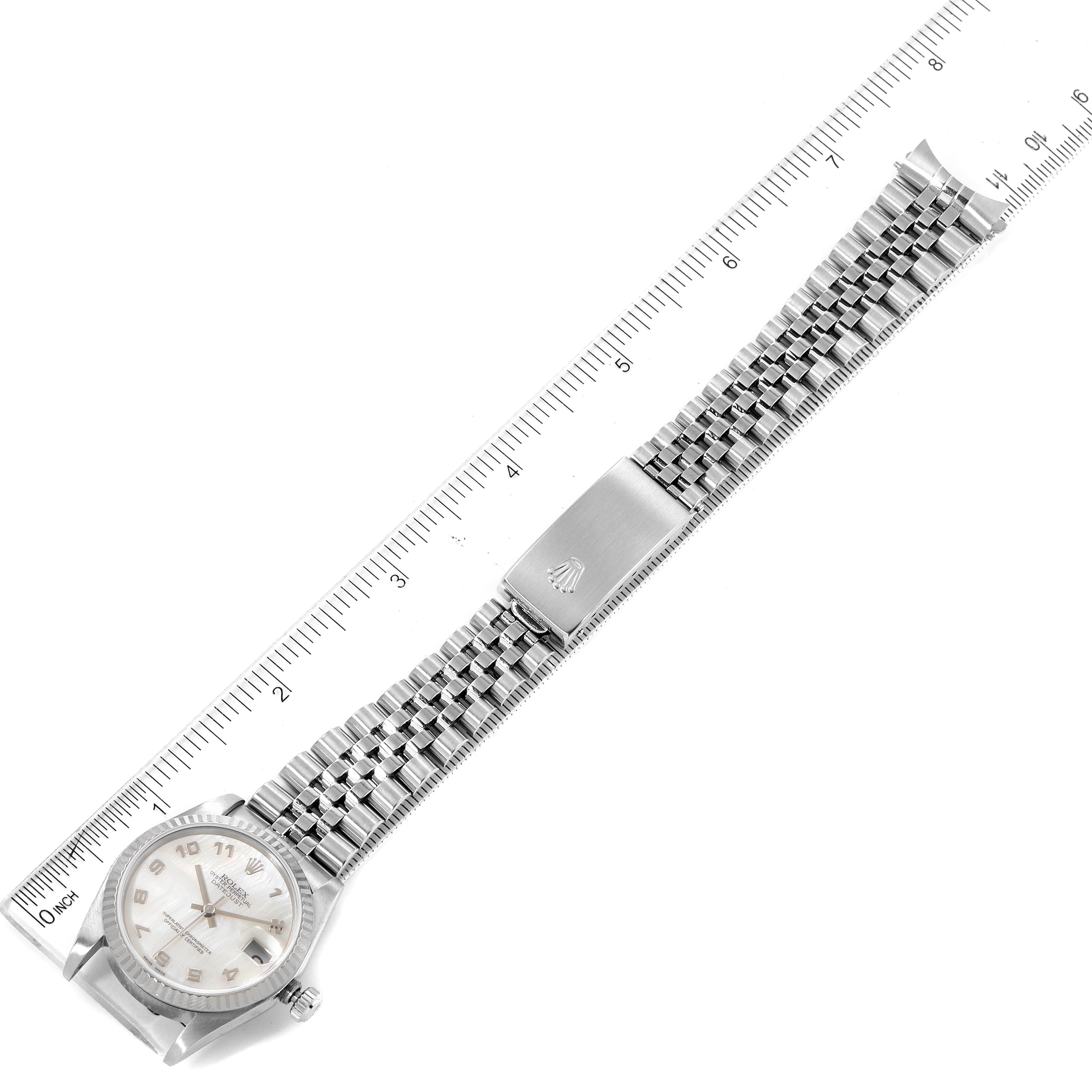 The image shows a top view of a Rolex Mid-Size 78274 Women
s Stainless Steel White Dial 78274 Women
s Stainless Steel White Dial watch with its face, bracelet, and clasp laid out beside a ruler.