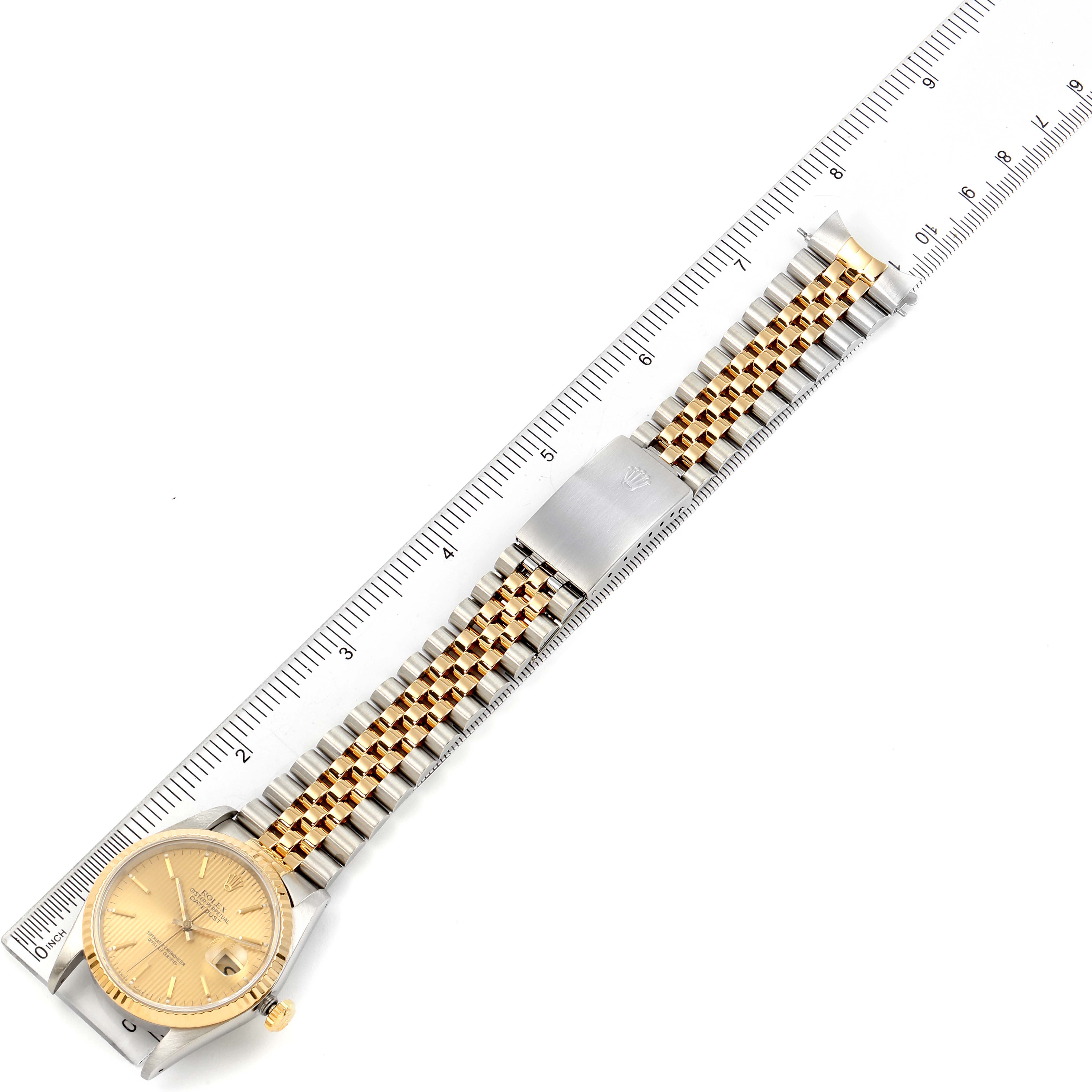 The image shows a top-down view of a Rolex Datejust 16233 Men's Steel and Gold (two tone) Champagne Dial 16233 Men's Steel and Gold (two tone) Champagne Dial watch, including its dial, crown, and metal bracelet on a ruler for measurement.