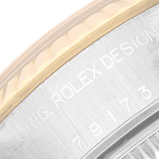 The image shows a close-up of the side of a Rolex Datejust 79173 Women's Steel and Gold (two tone) Black Dial 79173 Women's Steel and Gold (two tone) Black Dial watch, including the fluted bezel and engraved serial number.