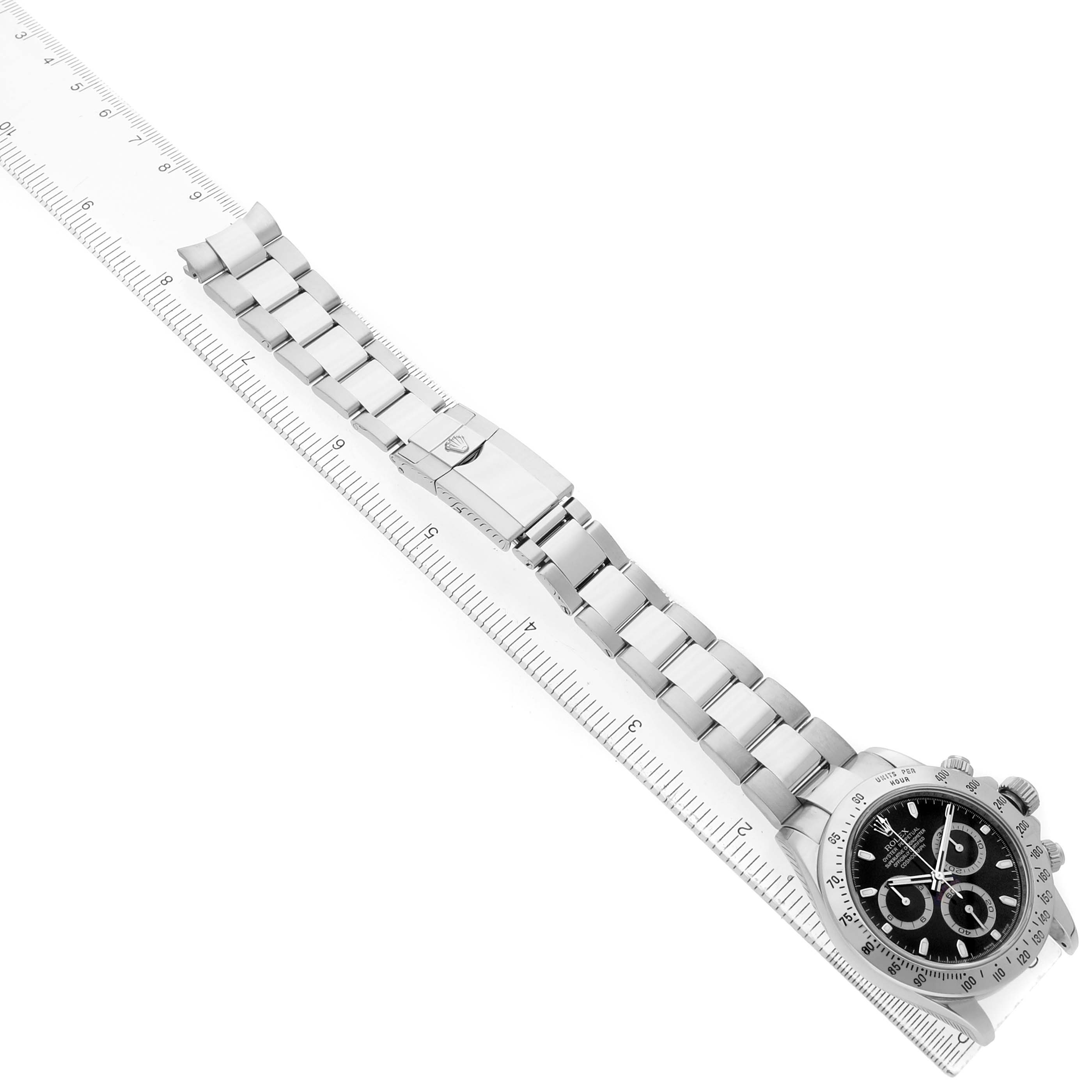 The Rolex Daytona 116520 Men's Stainless Steel Black Dial watch is shown from a top-down angle, highlighting the face, bracelet, and clasp alongside a ruler for scale.