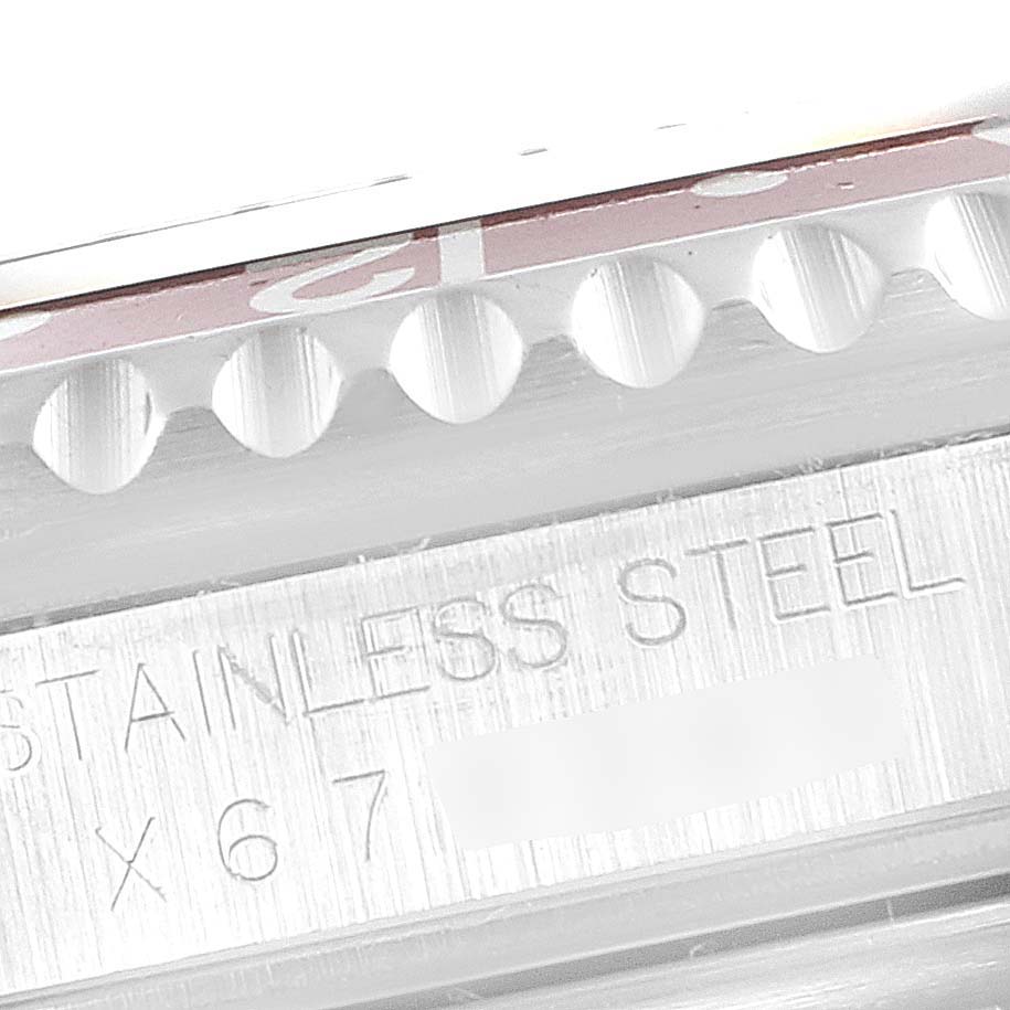 This close-up image shows the engraved stainless steel case and the edge of the bezel of a Rolex GMT-Master 16710 Men's Stainless Steel Black Dial 16710 Men's Stainless Steel Black Dial watch.