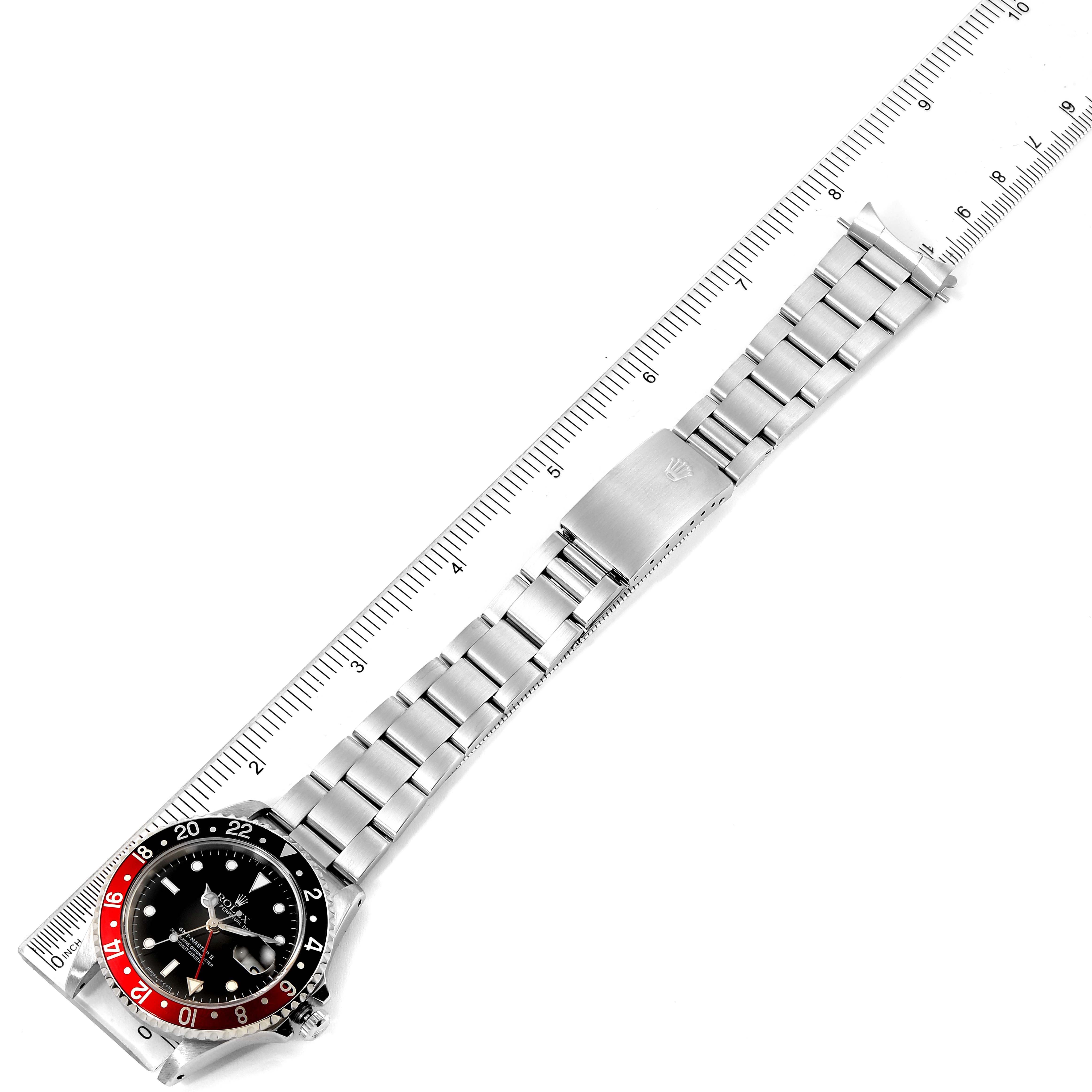 The image shows a top-down view of a Rolex GMT-Master 16710 Men's Stainless Steel Black Dial 16710 Men's Stainless Steel Black Dial with its full bracelet and clasp displayed alongside a ruler.