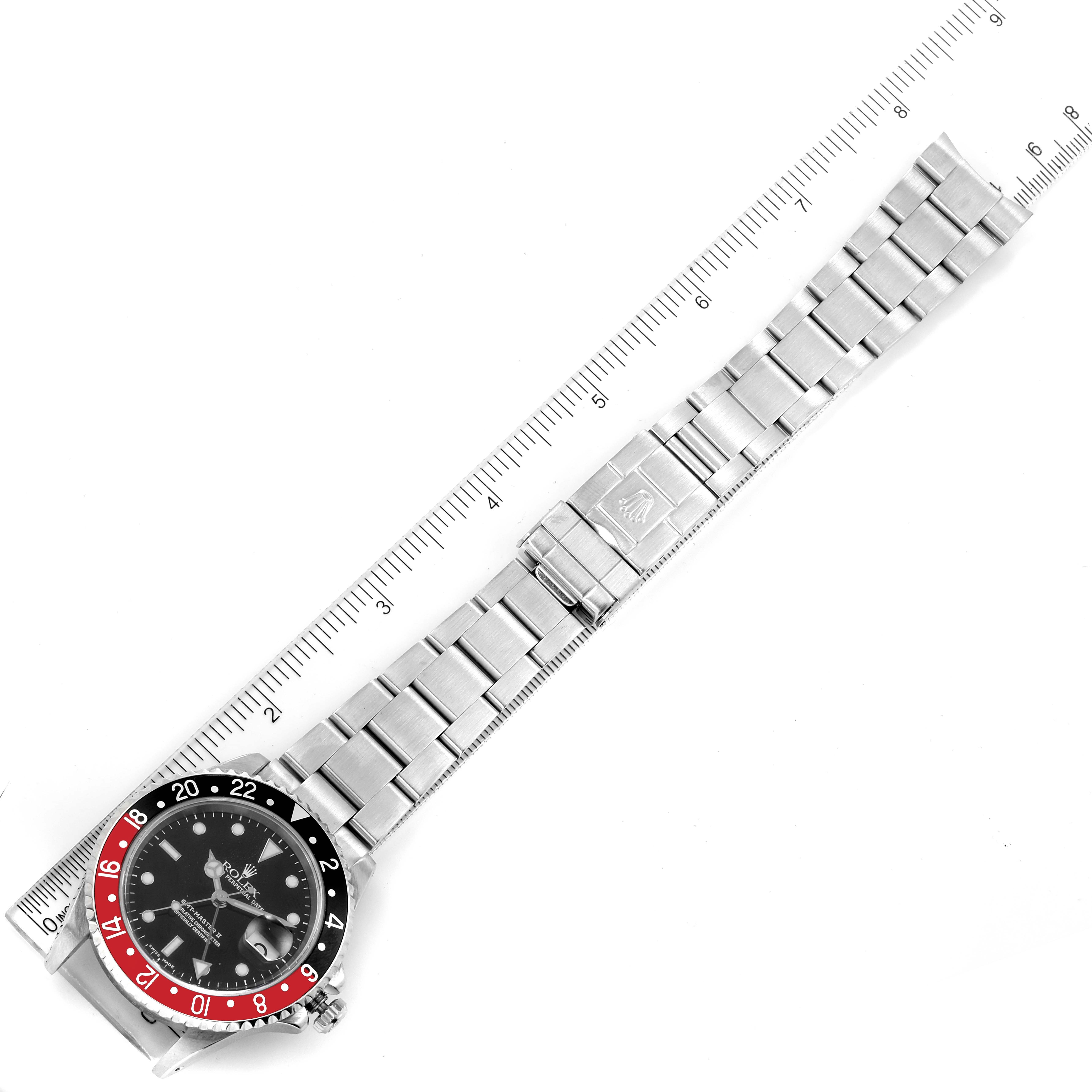 The image shows a Rolex GMT-Master 16710 Men
s Stainless Steel Black Dial 16710 Men
s Stainless Steel Black Dial watch laid flat, displaying the watch face and the entire bracelet alongside a measuring ruler.