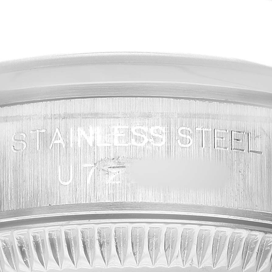 The image shows a close-up of the Rolex Oyster Perpetual 67180 Women's Stainless Steel Black Dial's case edge, highlighting the "STAINLESS STEEL" engraving.