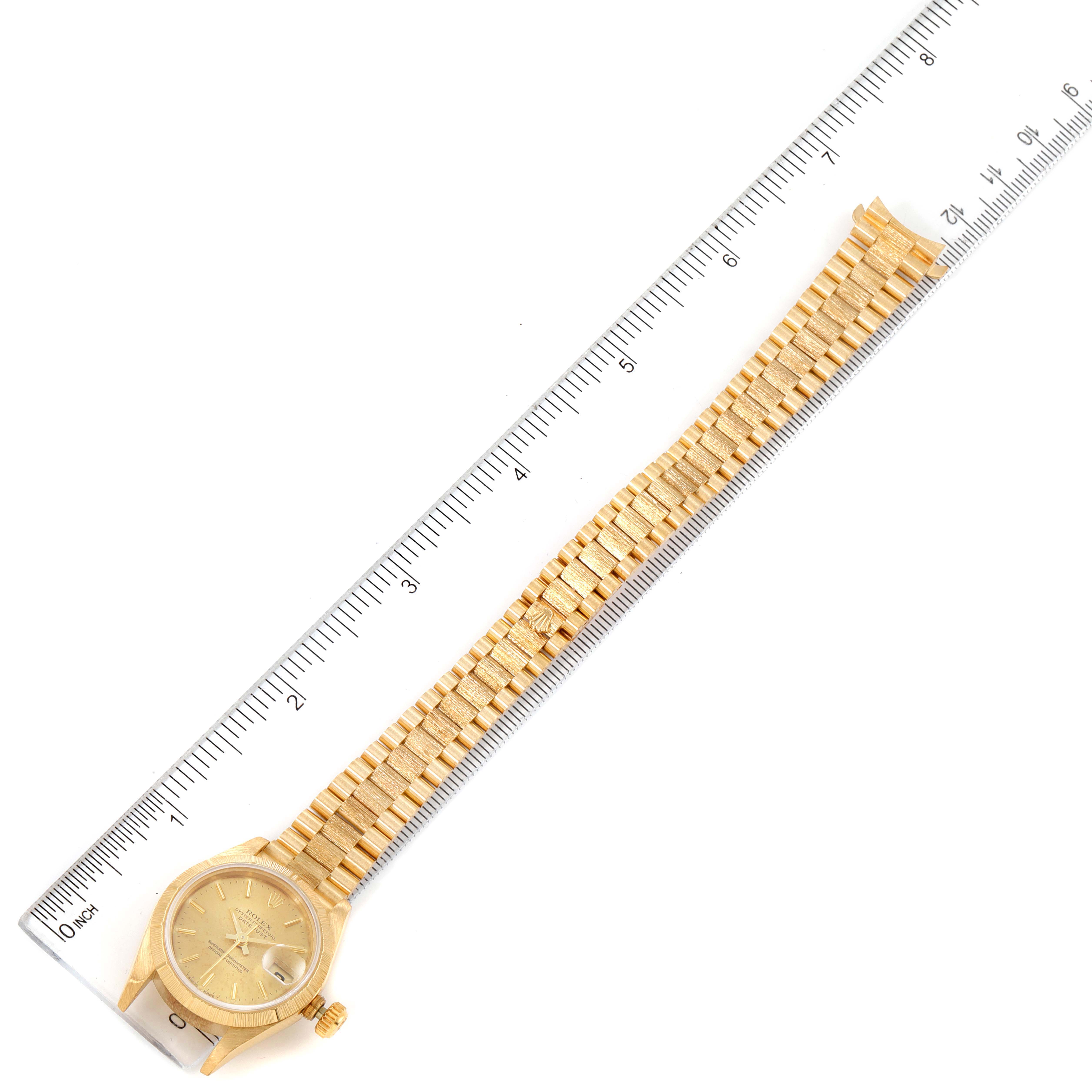 The image shows a top-down view of a Rolex President 69278 Women's Yellow Gold Champagne Dial 69278 Women's Yellow Gold Champagne Dial model watch with its band measured against a ruler.