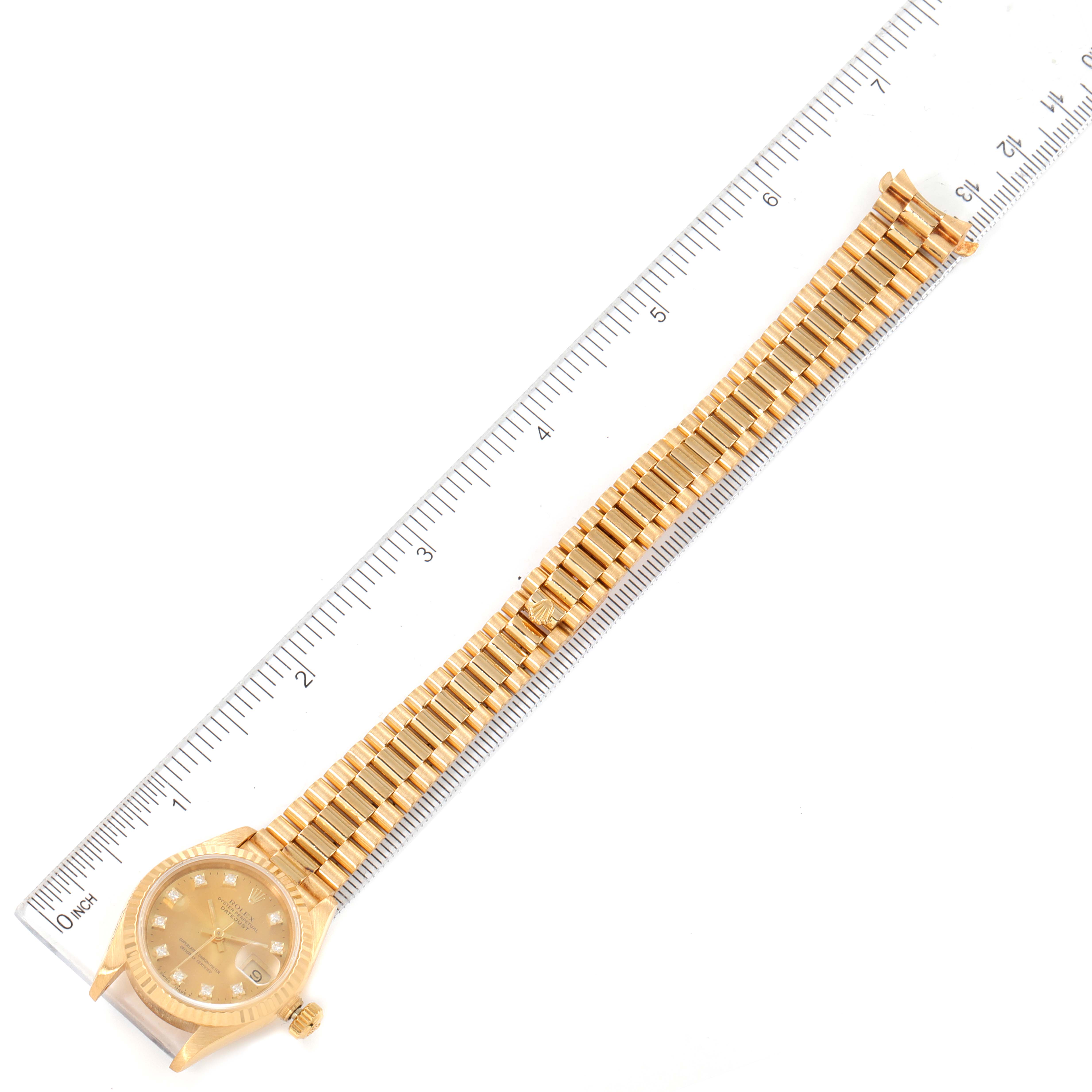The image shows the Rolex President 69178 Women
s Yellow Gold Champagne Dial 69178 Women
s Yellow Gold Champagne Dial model watch, including the full bracelet and the dial, with a ruler for scale.