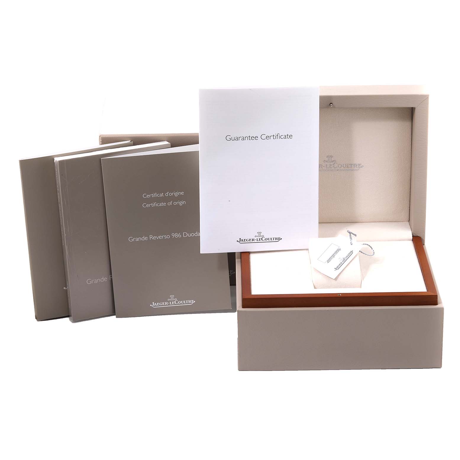 The image shows the packaging and documentation for a Jaeger-LeCoultre Reverso model, including guarantee certificates and the watch box.