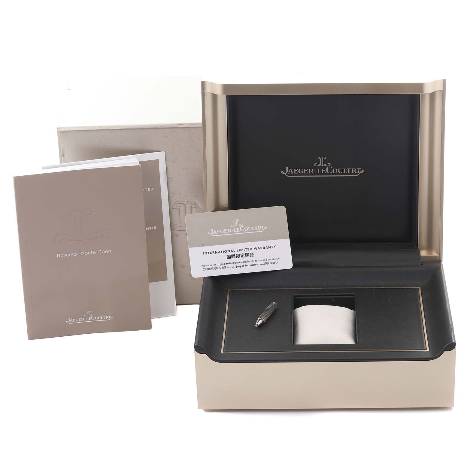 The image shows the packaging and accessories for a Jaeger-LeCoultre Reverso model, including the box, warranty card, and manuals.