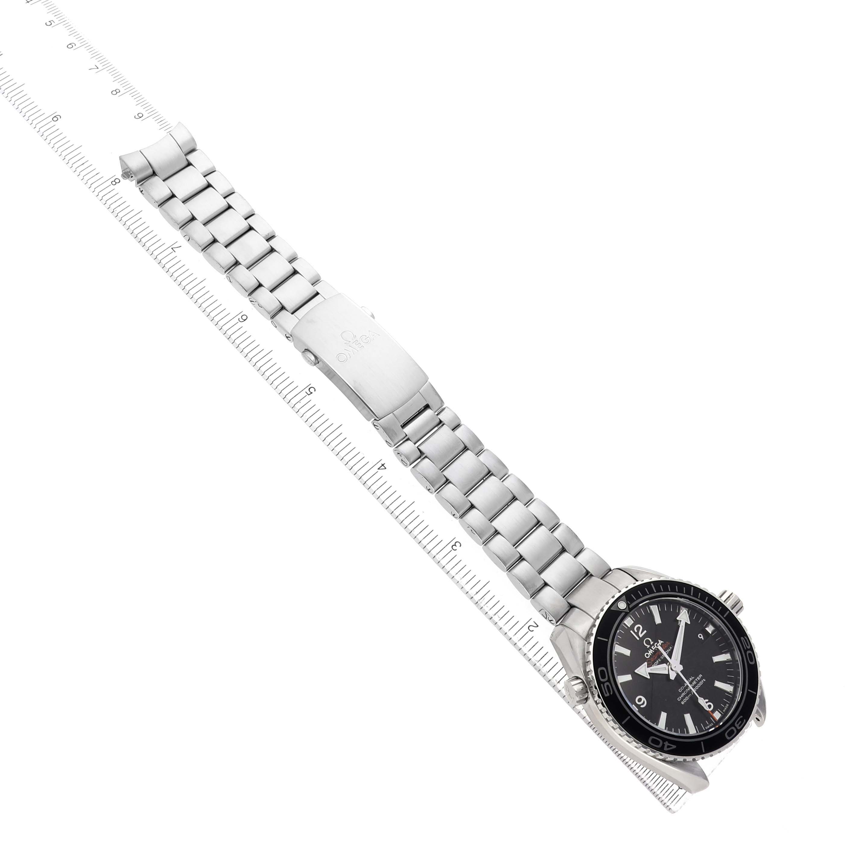 The Omega Seamaster 232.30.42.21.01.001 Men's Stainless Steel Black Dial watch is shown at a diagonal angle, highlighting the stainless steel bracelet and clasp, alongside a marked ruler.