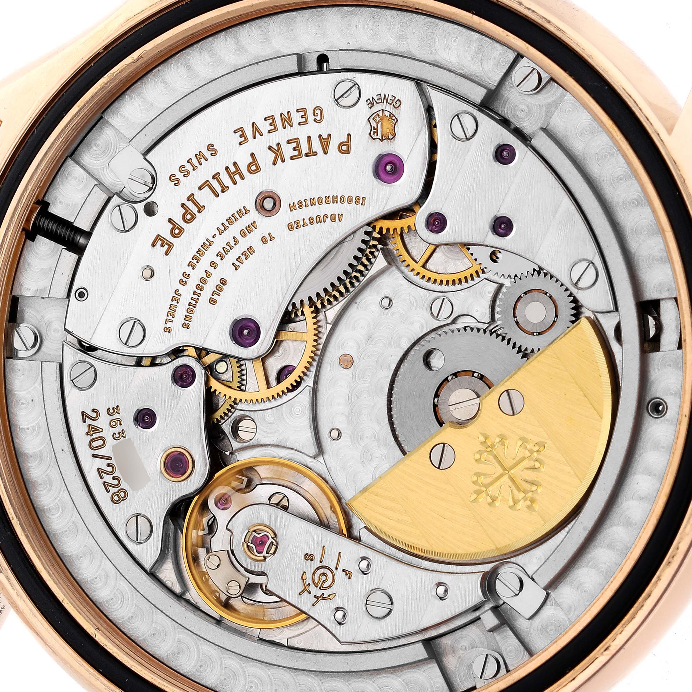 The image shows the movement mechanism of the Patek Philippe Complications 5130R-001 Men's Rose Gold Silver Dial 5130R-001 Men's Rose Gold Silver Dial watch, highlighting its gears and intricate components.