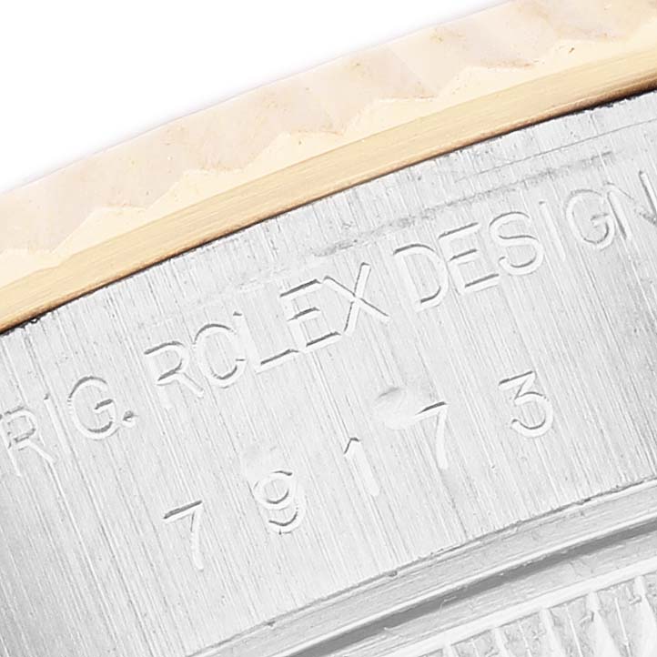 The image shows a close-up of the Rolex Datejust 79173 Women's Steel and Gold (two tone) Champagne Dial's outer case, highlighting the engraved design and serial numbers.