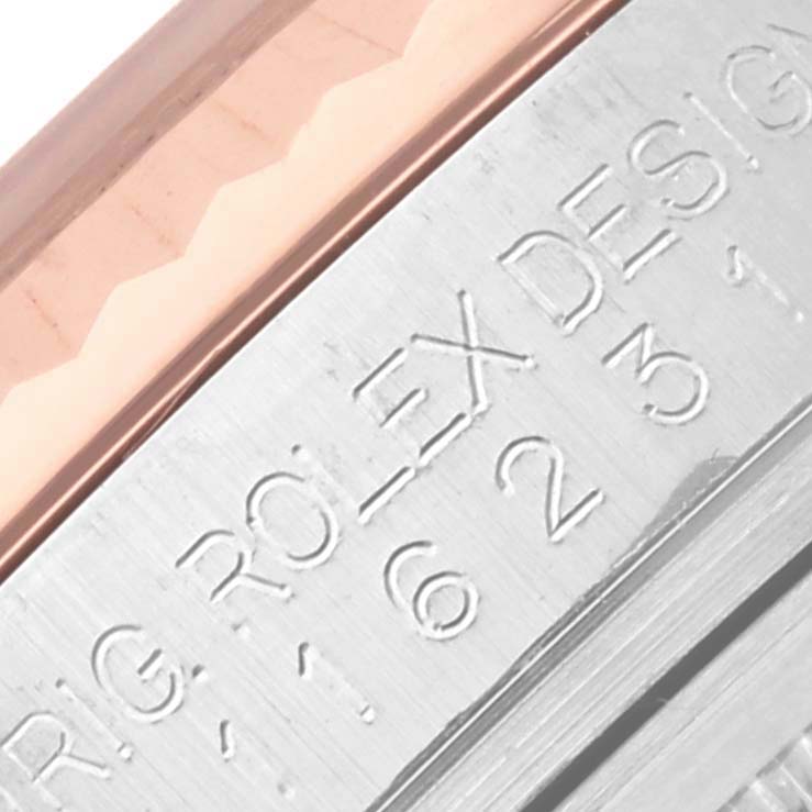 The image shows an angled close-up of a Rolex Datejust 116231 Men's Steel and Gold (two tone) Pink Dial 116231 Men's Steel and Gold (two tone) Pink Dial case's side with engraved text.