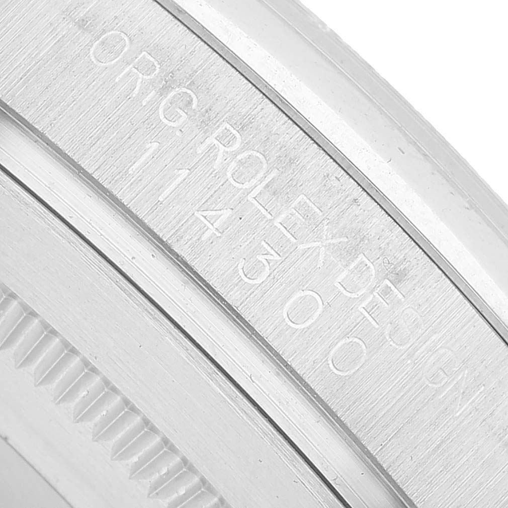 The image shows the engraved side of the bezel on a Rolex Oyster Perpetual 114300 Men's Stainless Steel Blue Dial watch.