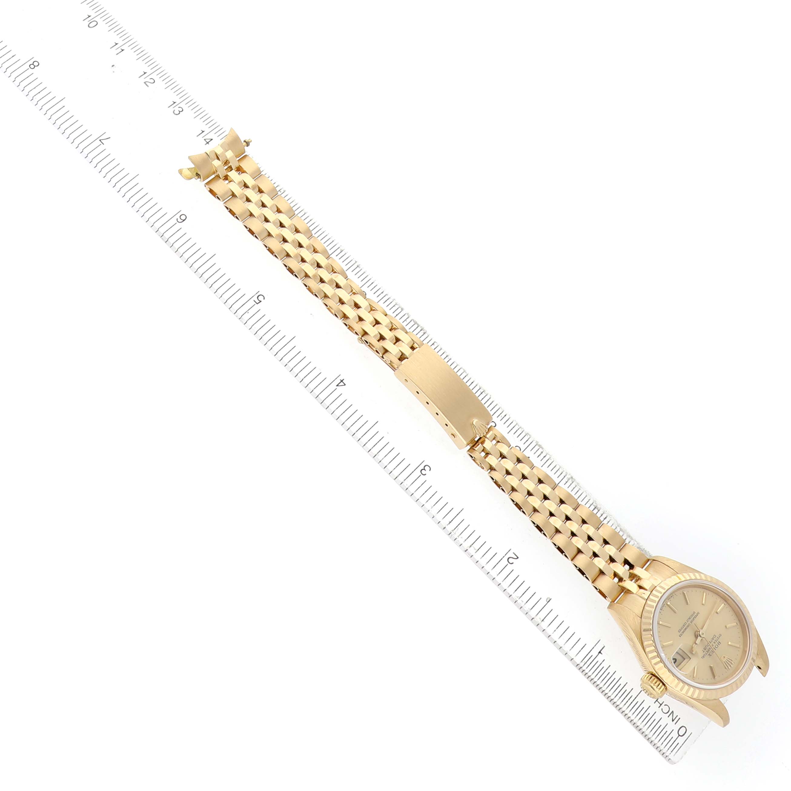 The Rolex President 69178 Women's Yellow Gold Champagne Dial watch is shown from a top-down angle, featuring the bracelet and clasp alongside a ruler for scale.