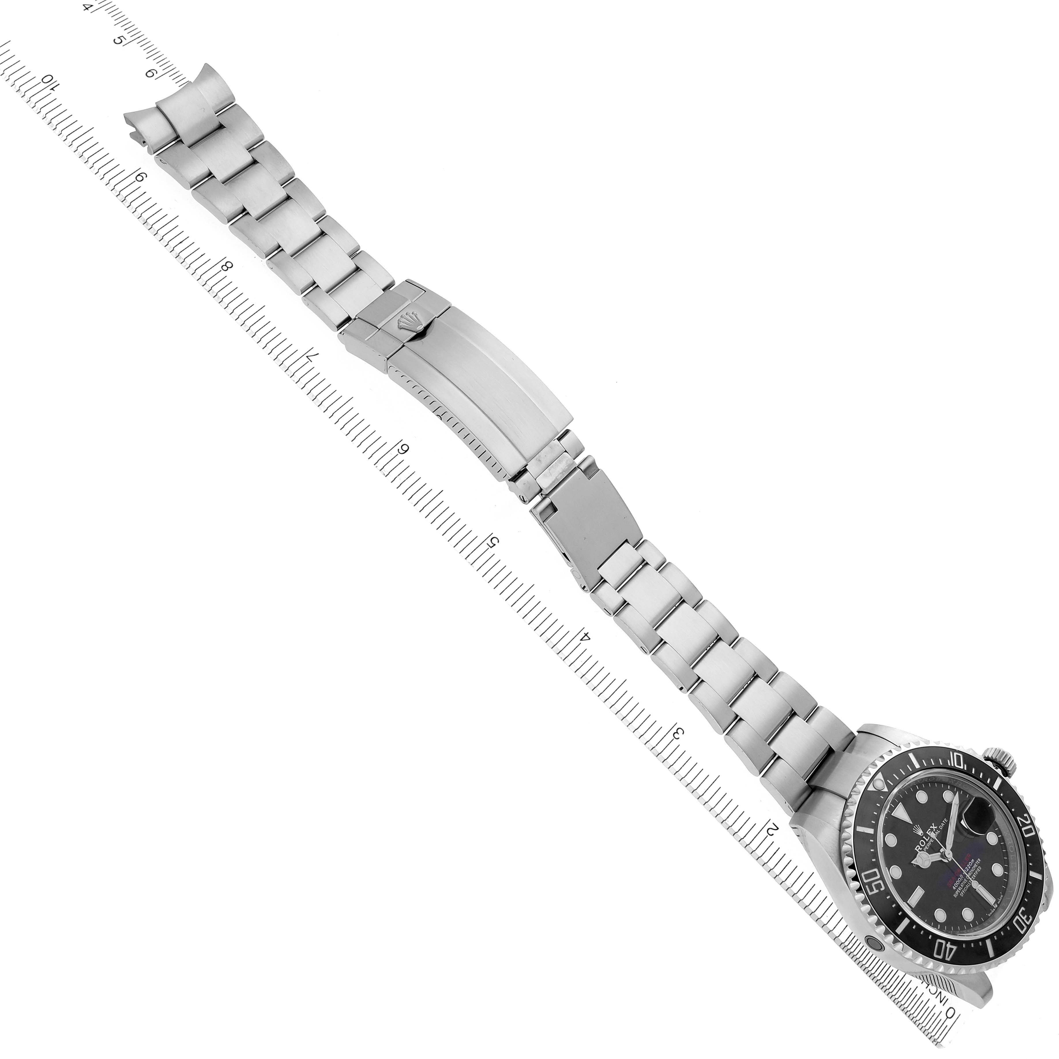 The image shows a top-down view of a Rolex Sea-Dweller 126600 Men's Stainless Steel Black Dial 126600 Men's Stainless Steel Black Dial watch with its full bracelet and clasp visible, aligned with a ruler.