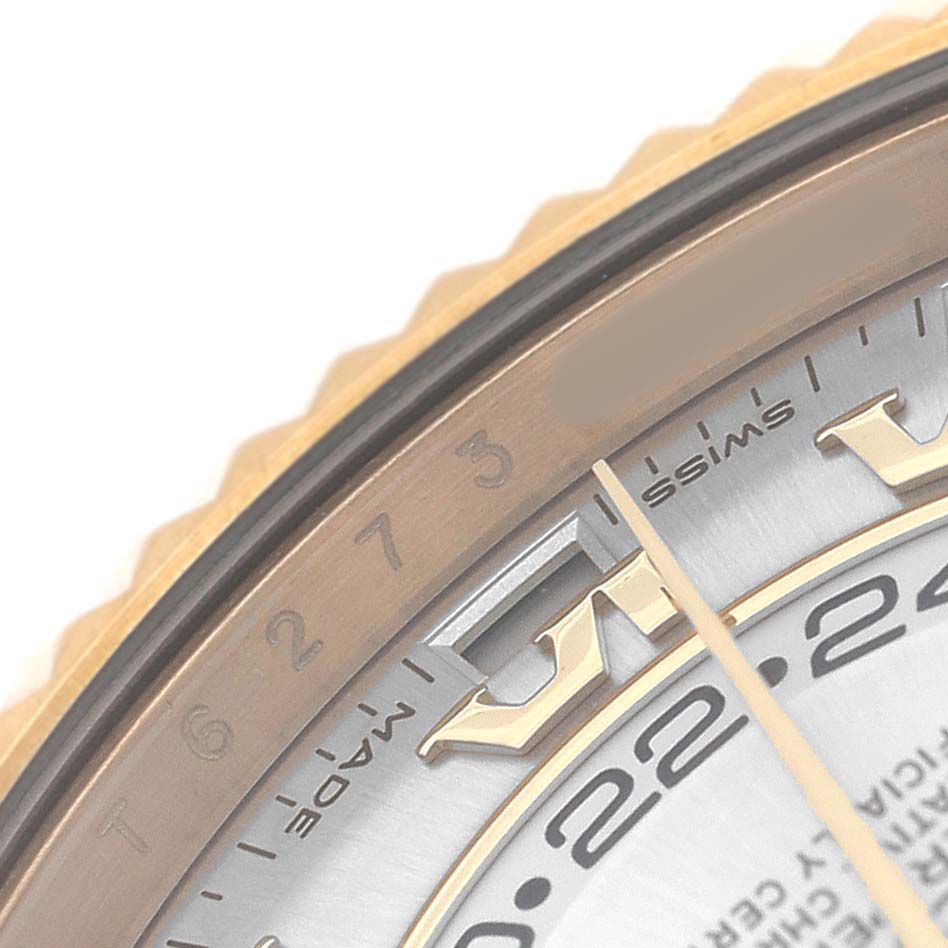 The image shows a close-up of the Rolex Sky-Dweller 326138 Men's Yellow Gold Silver Dial's bezel, part of the dial, and hand, focusing on the intricate detailing.