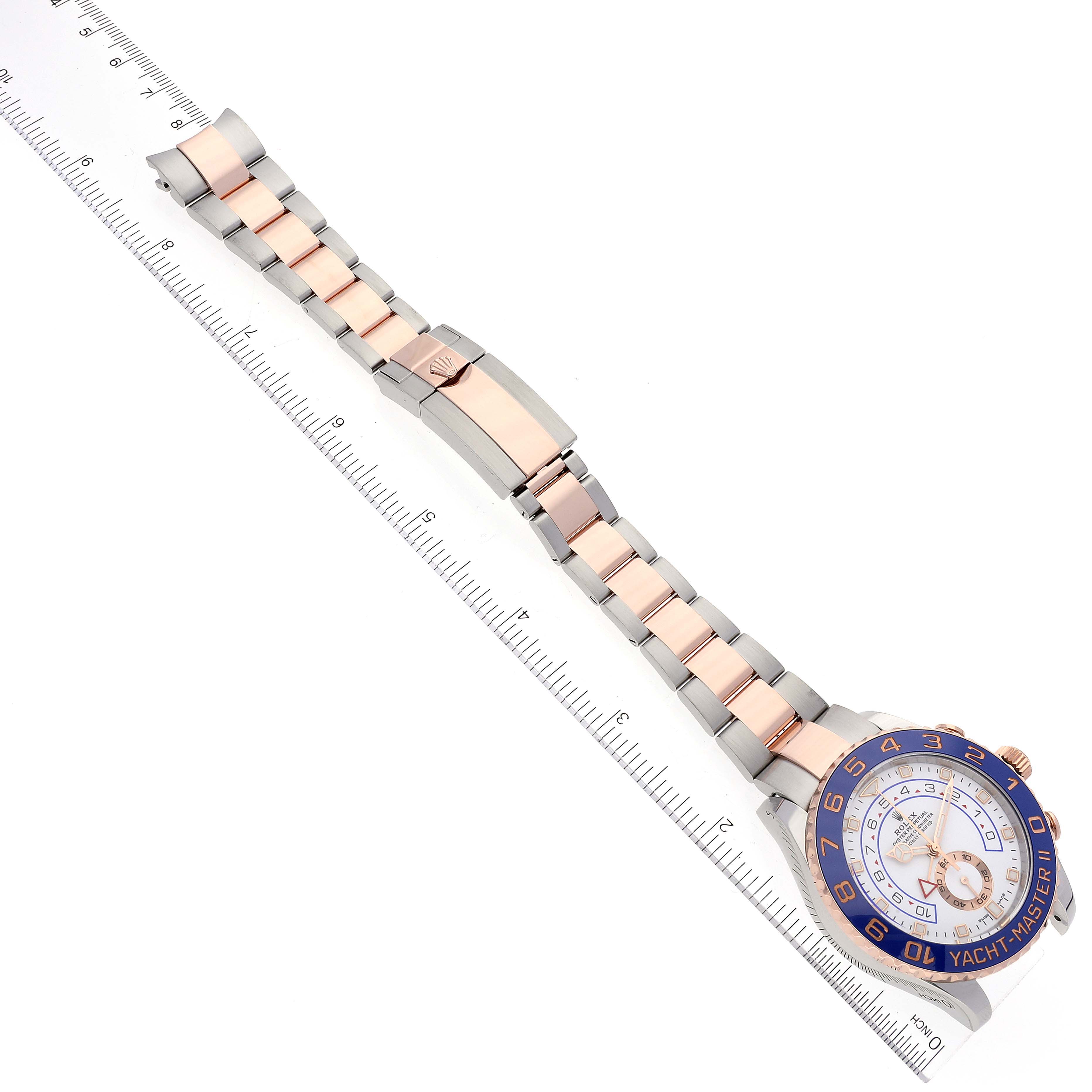 The image shows the Rolex Yacht-Master 116681 Men
s Steel and Gold (two tone) White Dial 116681 Men
s Steel and Gold (two tone) White Dial watch placed diagonally with the strap and face visible, next to a measuring ruler.
