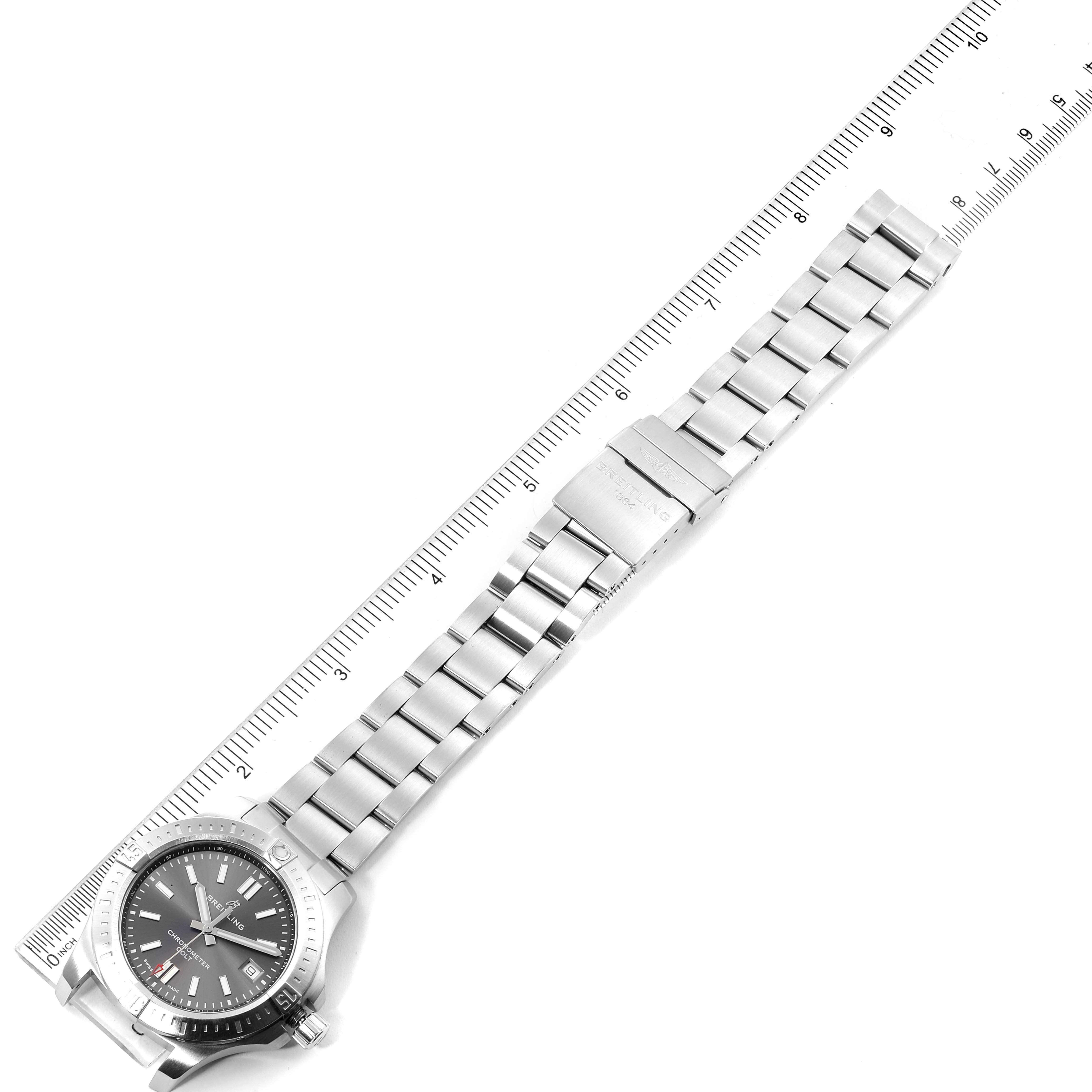 The image shows a Breitling Colt A17313 Men
s Stainless Steel Grey Dial A17313 Men
s Stainless Steel Grey Dial watch laid flat with its stainless steel bracelet extended alongside a ruler for measurement.