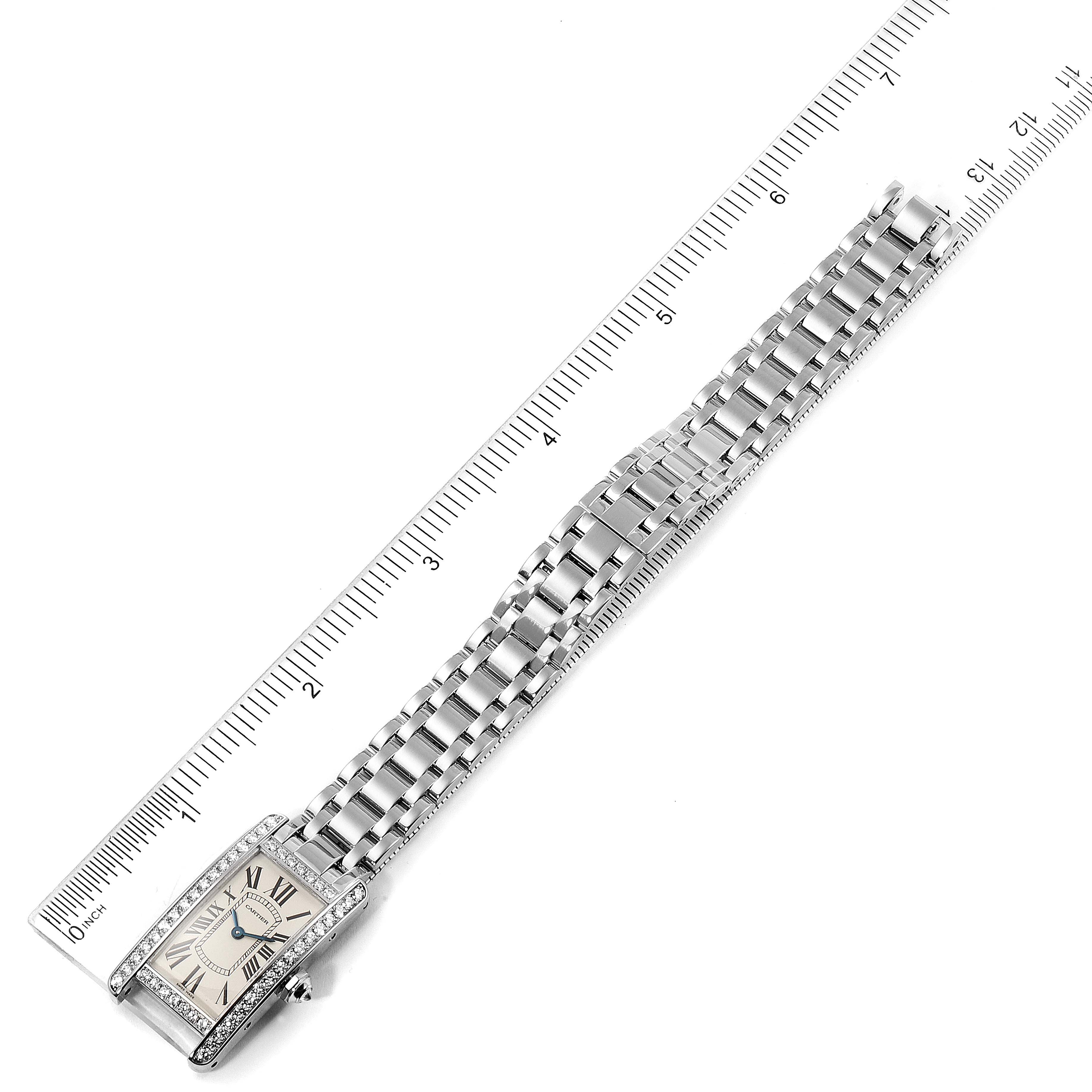 The image shows a Cartier Tank Americaine WB7073L1 Women's White Gold Silver Dial WB7073L1 Women's White Gold Silver Dial watch placed horizontally with its face, bracelet, and a ruler for scale.