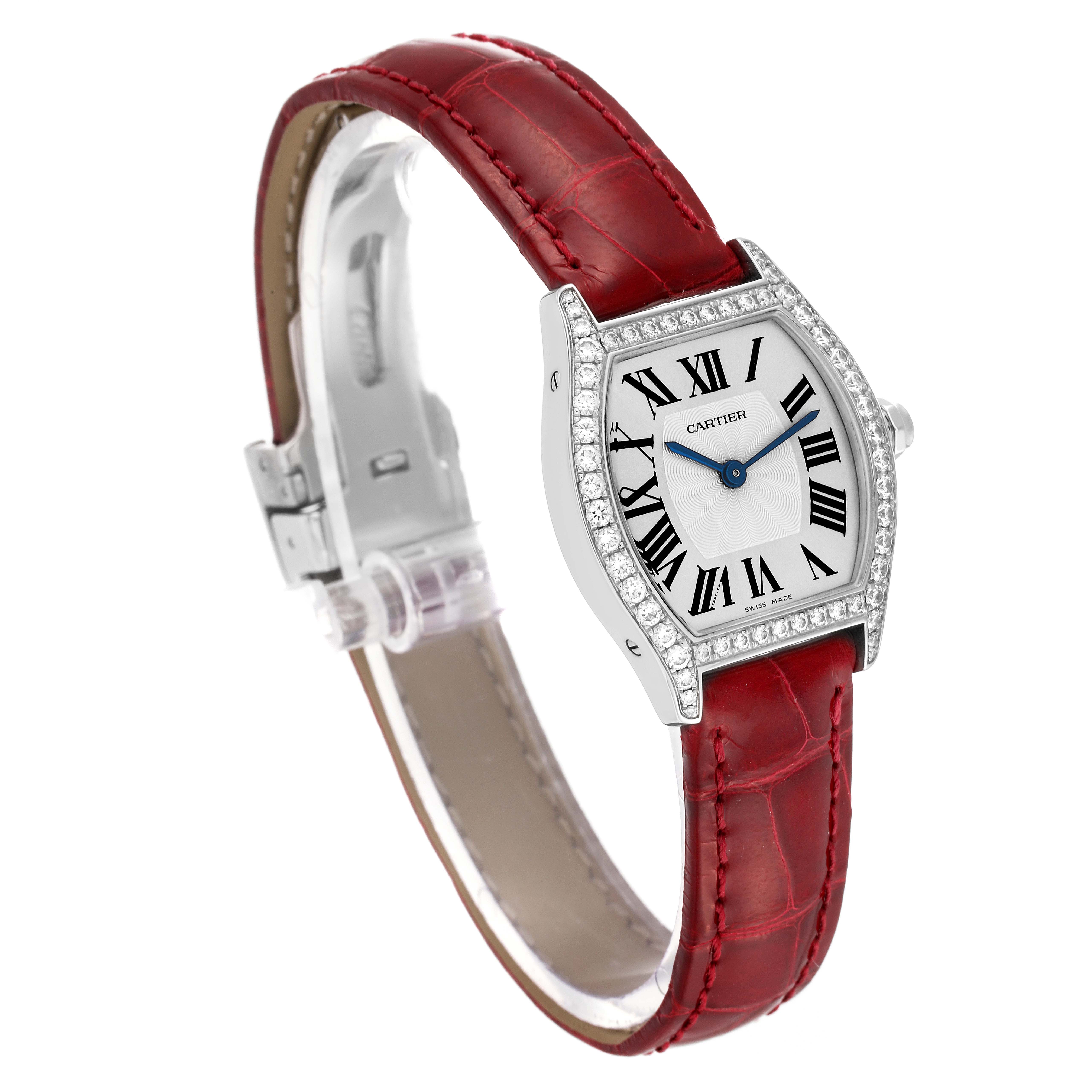 This image shows a Cartier Tortue WA501007 Women's White Gold Silver Dial WA501007 Women's White Gold Silver Dial watch at an angled side view, displaying its red leather strap, diamond-encrusted bezel, and Roman numeral dial.