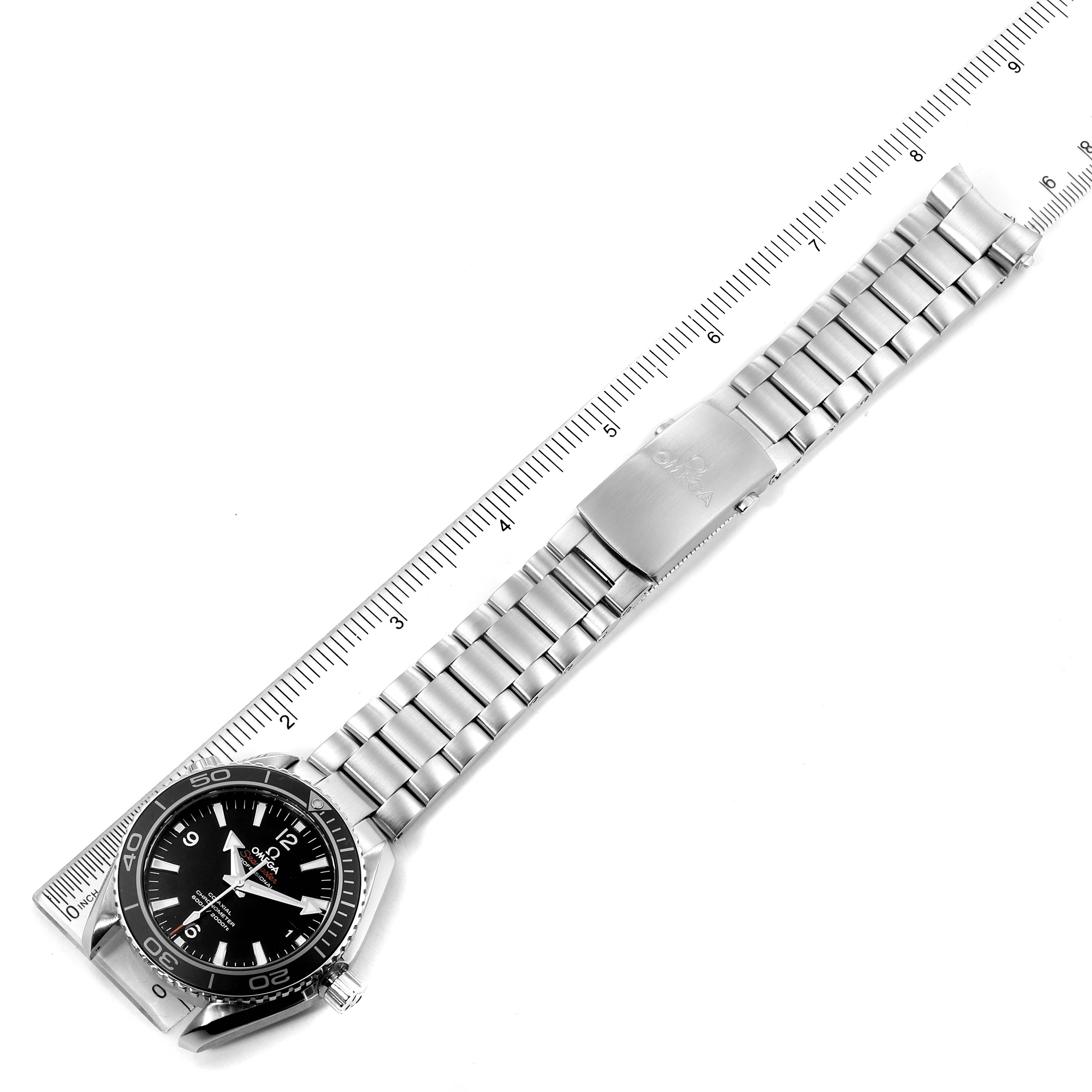 The image shows an Omega Planet Ocean 232.30.42.21.01.003 Men
s Stainless Steel Black Dial 232.30.42.21.01.003 Men
s Stainless Steel Black Dial watch in a top-down view, displaying the face, bracelet, and clasp alongside a measuring ruler.