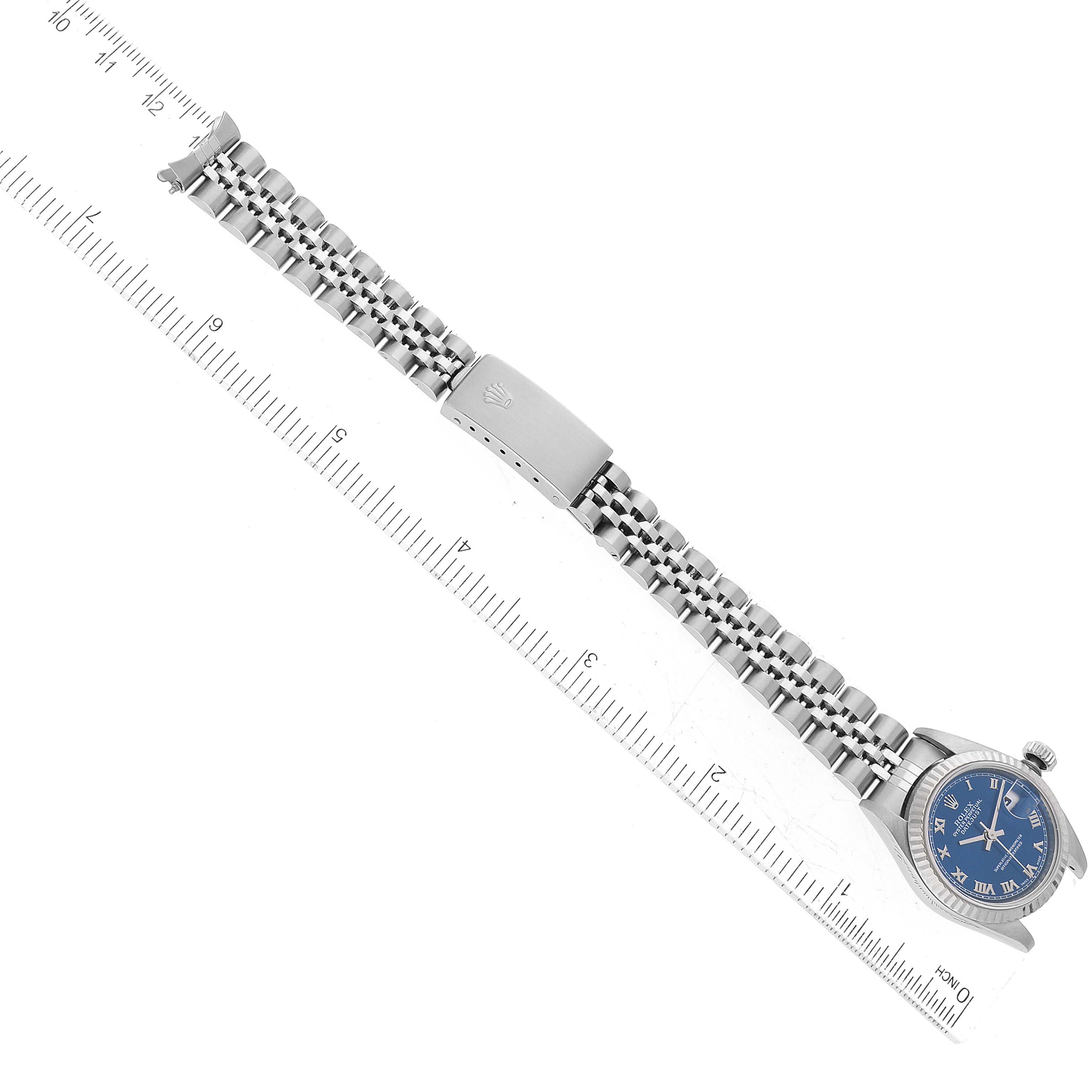 The Rolex Datejust 79174 Women's Stainless Steel Blue Dial 79174 Women's Stainless Steel Blue Dial watch is shown from a top-down angle, displaying the band, dial, and clasp against a measuring ruler.