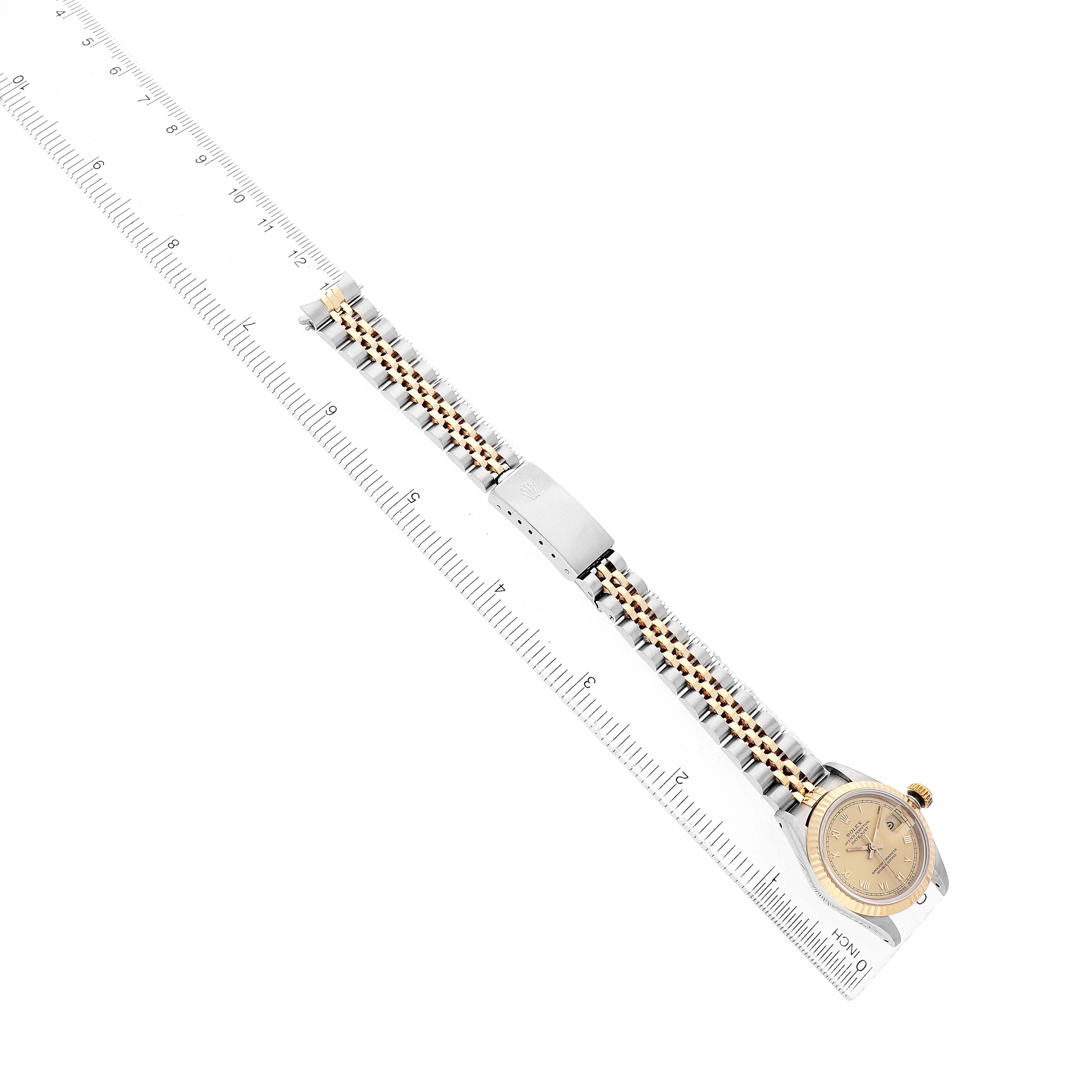 The Rolex Datejust 69173 Women's Stainless Steel Champagne Dial watch is shown at a diagonal angle, highlighting the bracelet and clasp alongside a ruler.