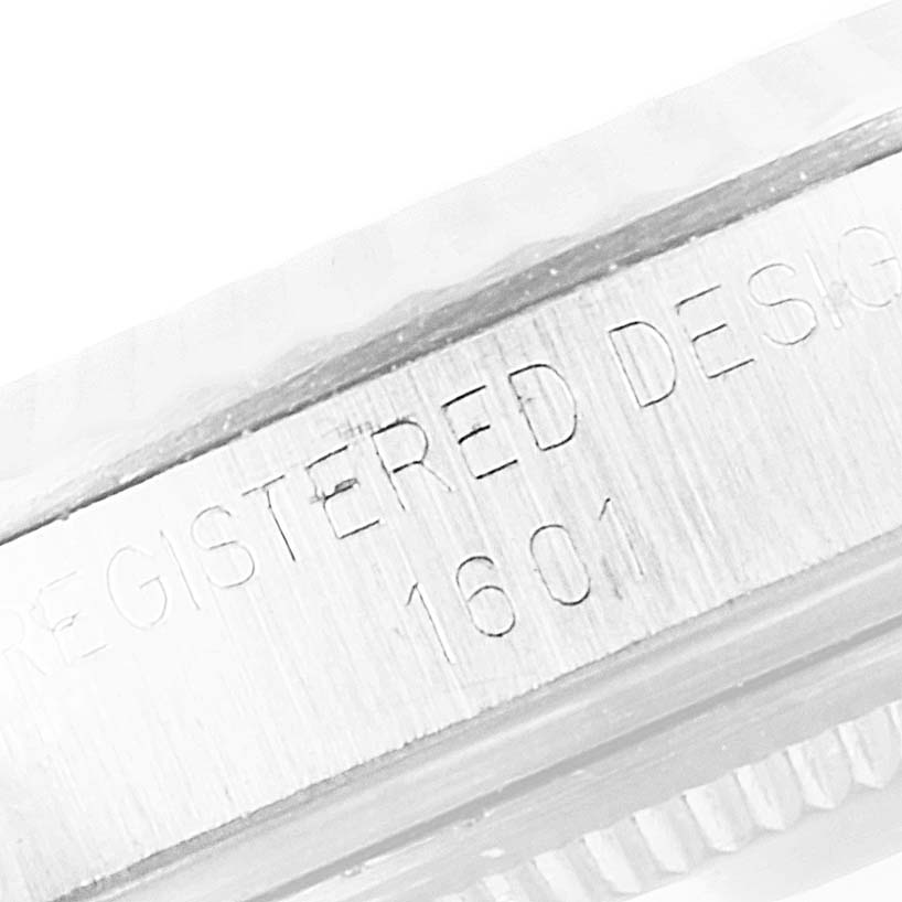 This image shows a close-up of the side of the Rolex Vintage Collection 1601 Men's Stainless Steel Silver Dial 1601 Men's Stainless Steel Silver Dial model, with "REGISTERED DESIGN 1601" engraved on it.
