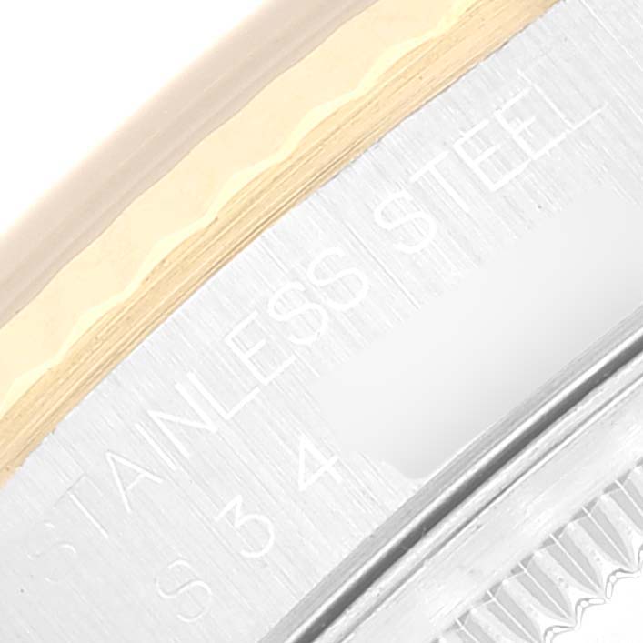 The image shows a close-up of a Rolex Datejust 16233 Men's Steel and Gold (two tone) Black Dial 16233 Men's Steel and Gold (two tone) Black Dial's stainless steel and gold bezel and part of the engraved serial number.