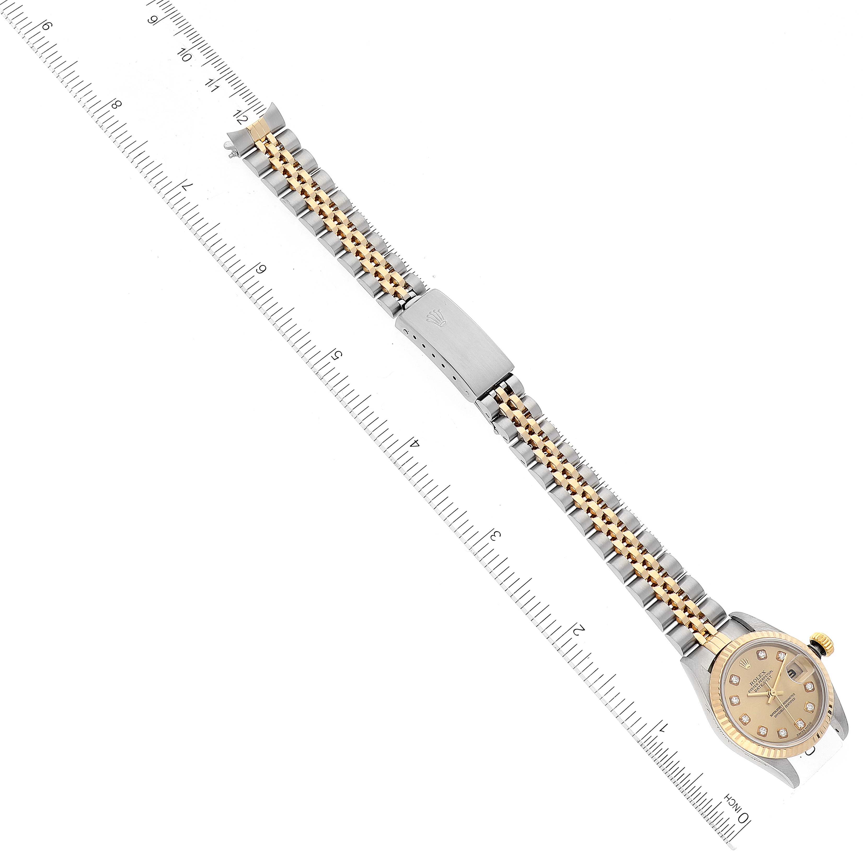 The image shows a Rolex Datejust 79173 Women's Steel and Gold (two tone) Champagne Dial 79173 Women's Steel and Gold (two tone) Champagne Dial watch laid flat, highlighting the face, bracelet, and clasp, alongside a ruler for size reference.