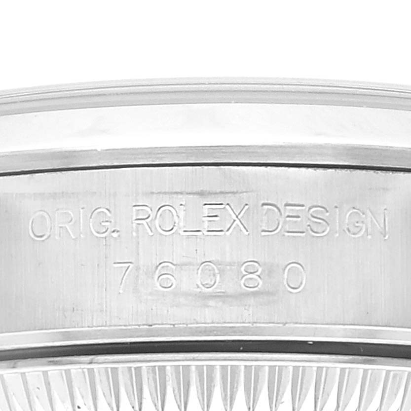 The image shows a close-up of the side of a Rolex Oyster Perpetual 76080 Women's Stainless Steel Black Dial 76080 Women's Stainless Steel Black Dial watch case with the inscription "Orig. Rolex Design 76080."