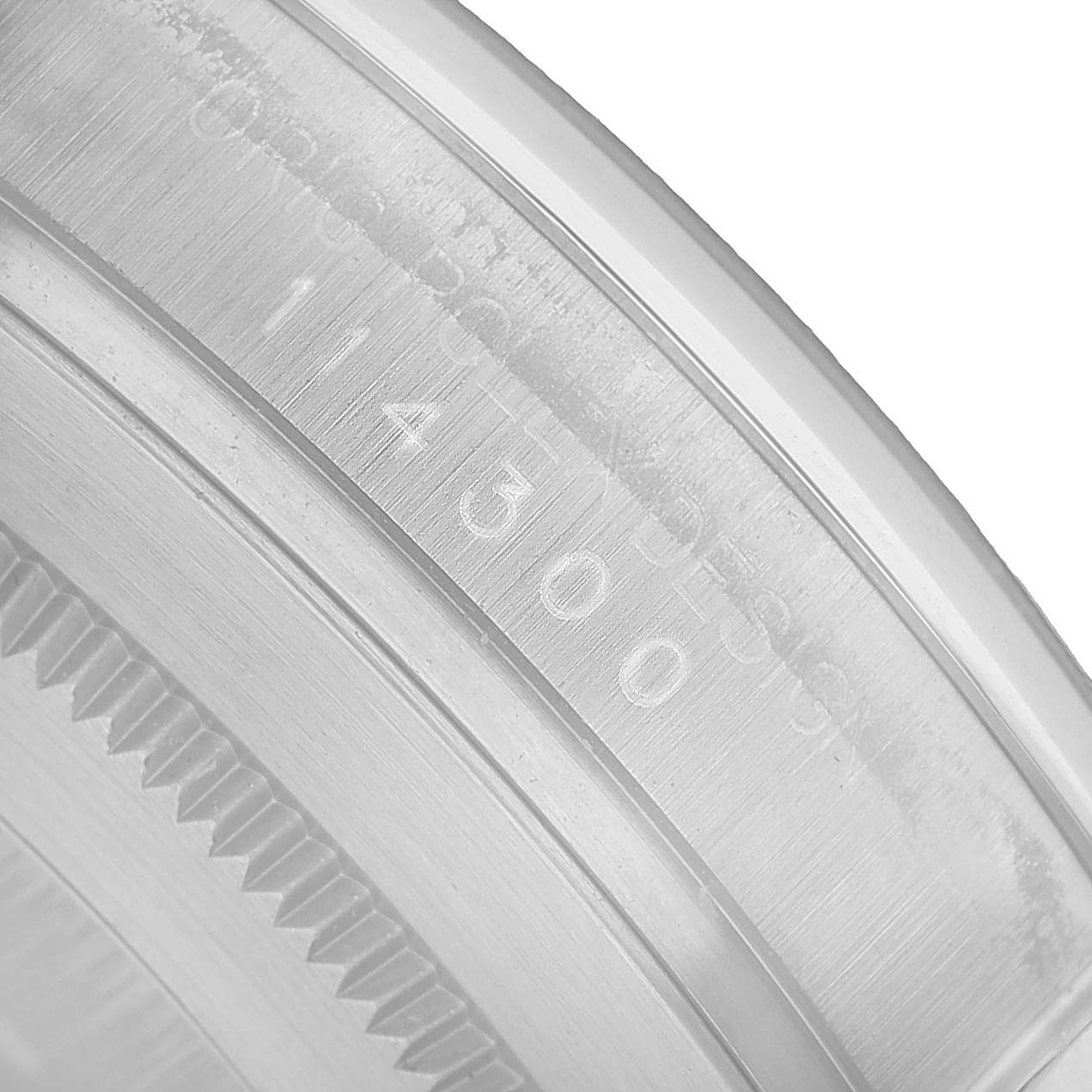 The image shows a close-up of the engraved bezel on a Rolex Oyster Perpetual 114300 Men's Stainless Steel Grey Dial watch.