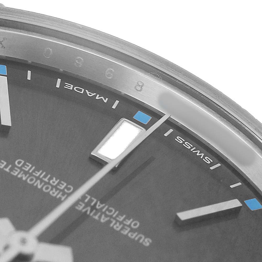 The image shows a close-up of the Rolex Oyster Perpetual 114300 Men's Stainless Steel Grey Dial watch face, highlighting the dial, markers, and part of the minute hand.