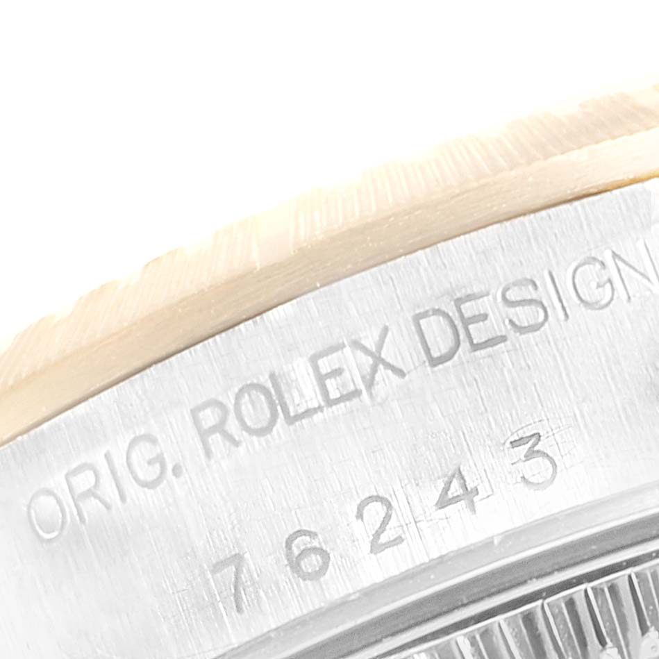 This image shows a close-up of the engraved design and serial number on the bezel of a Rolex Oyster Perpetual 76243 Women's Steel and Gold (two tone) Silver Dial 76243 Women's Steel and Gold (two tone) Silver Dial watch.
