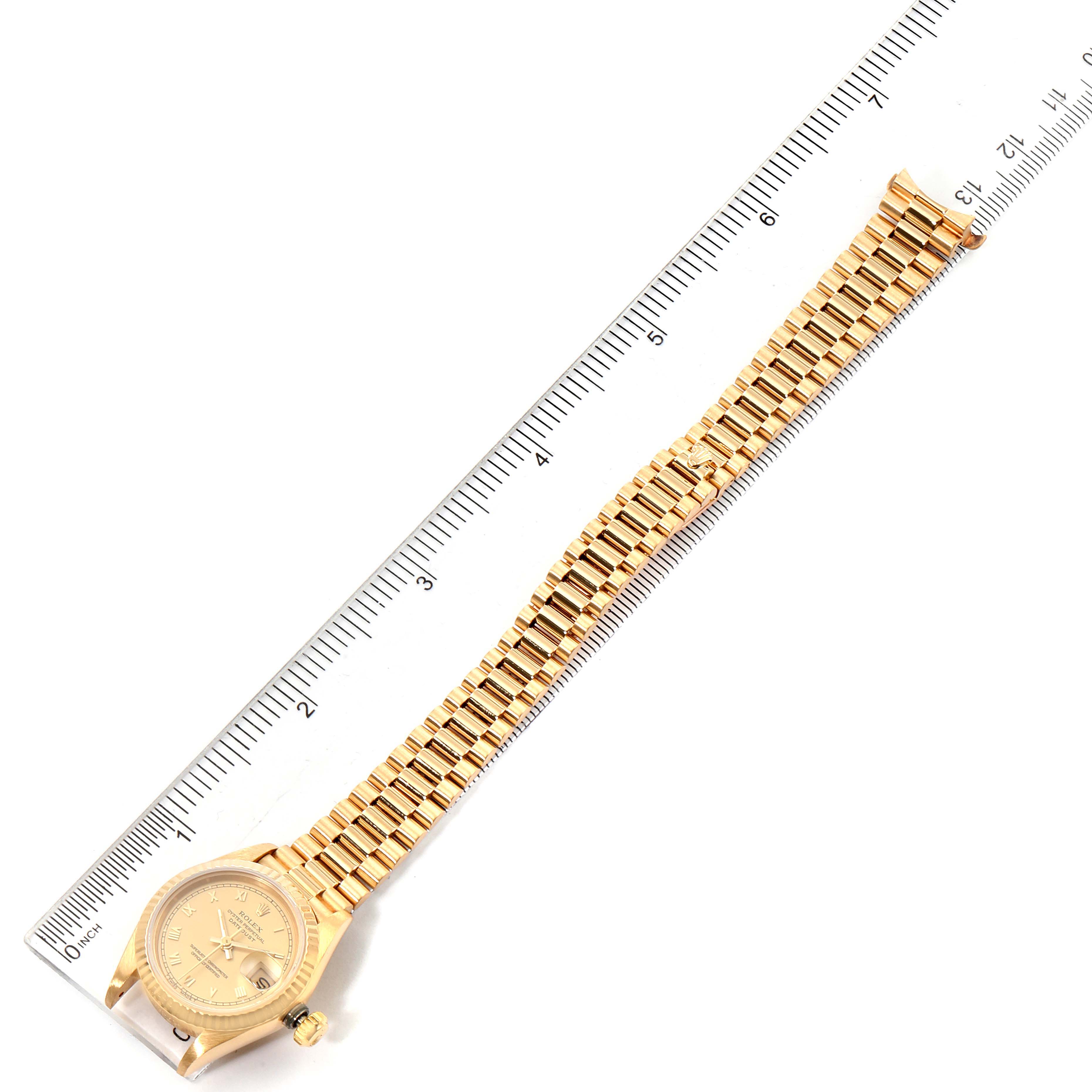 The image shows a top-down view of a Rolex President 69178 Women
s Yellow Gold Champagne Dial 69178 Women
s Yellow Gold Champagne Dial model watch, including its face, bezel, and full bracelet against a ruler.