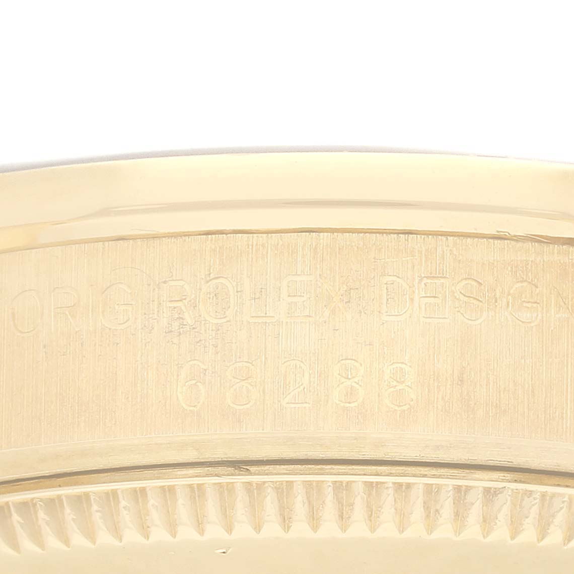 The image shows a close-up of the side engravings on a Rolex President 68288 Women's Yellow Gold Blue Dial 68288 Women's Yellow Gold Blue Dial model's gold case bezel.