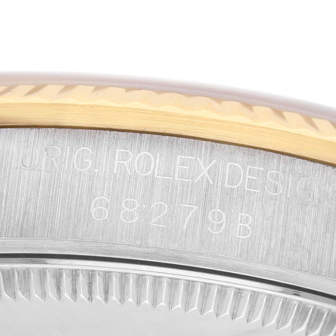 The image shows a close-up of the side of a Rolex President 68279 Women's White Gold Brown Dial watch, featuring engravings and part of the bezel.