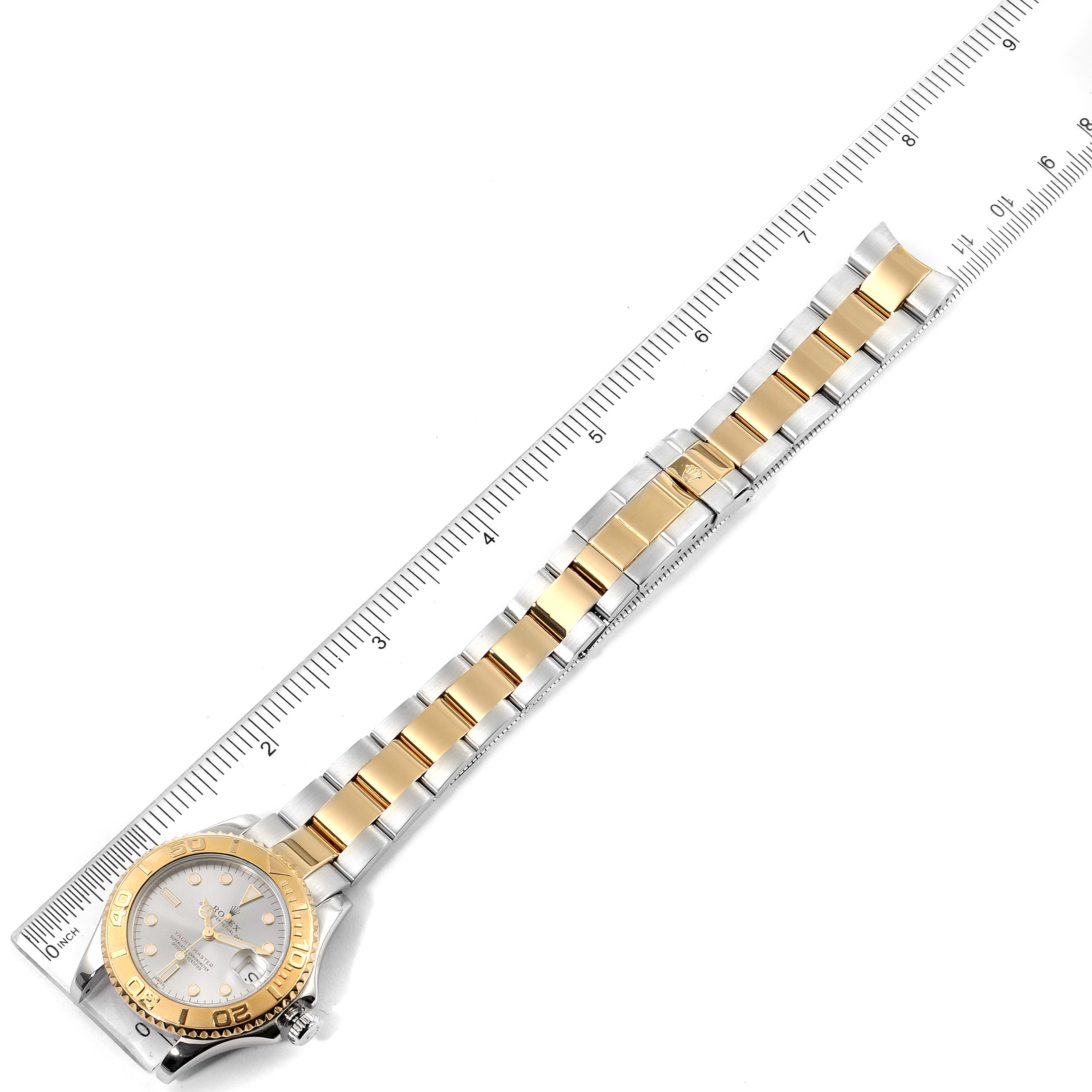 The Rolex Yacht-Master 68623 Men
s Steel and Gold (two tone) Grey Dial 68623 Men
s Steel and Gold (two tone) Grey Dial watch is shown from an overhead angle, displaying the entire band and face aligned with a ruler.