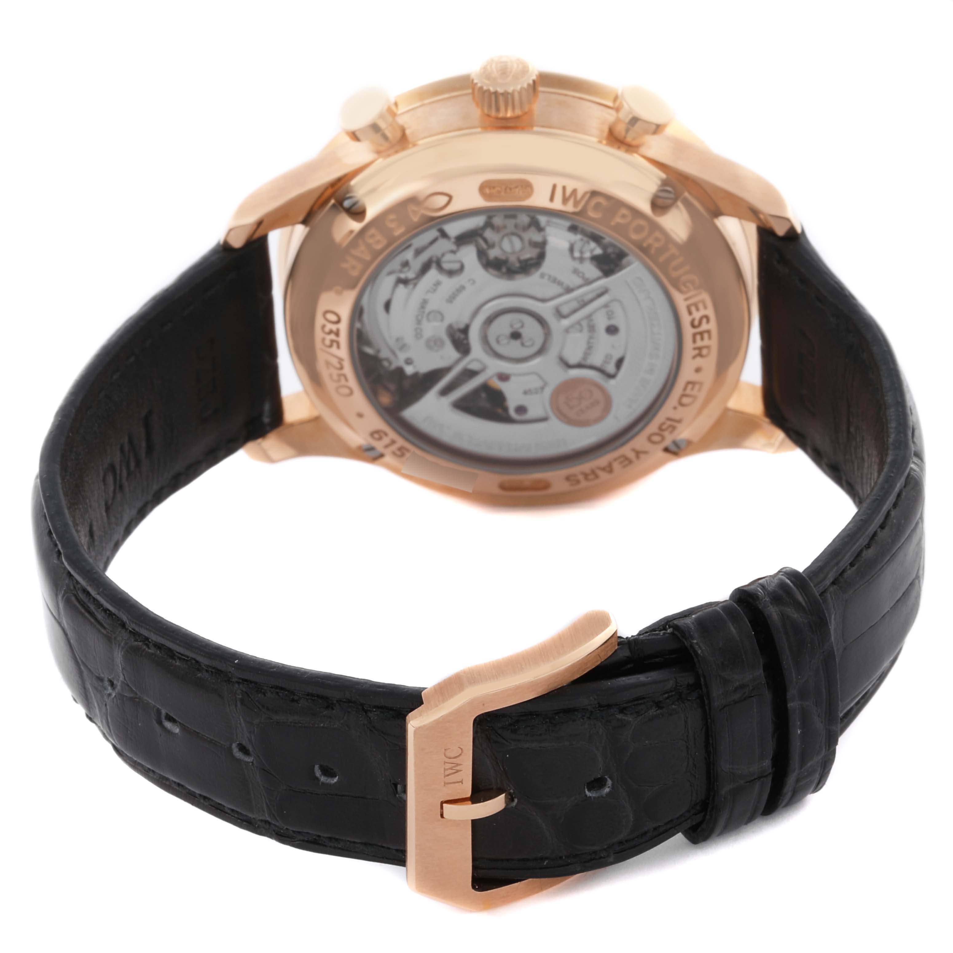The image shows the IWC Portuguese IW371603 Men's Rose Gold White Dial IW371603 Men's Rose Gold White Dial watch from the rear, revealing the mechanical movement and a leather strap with a clasp.