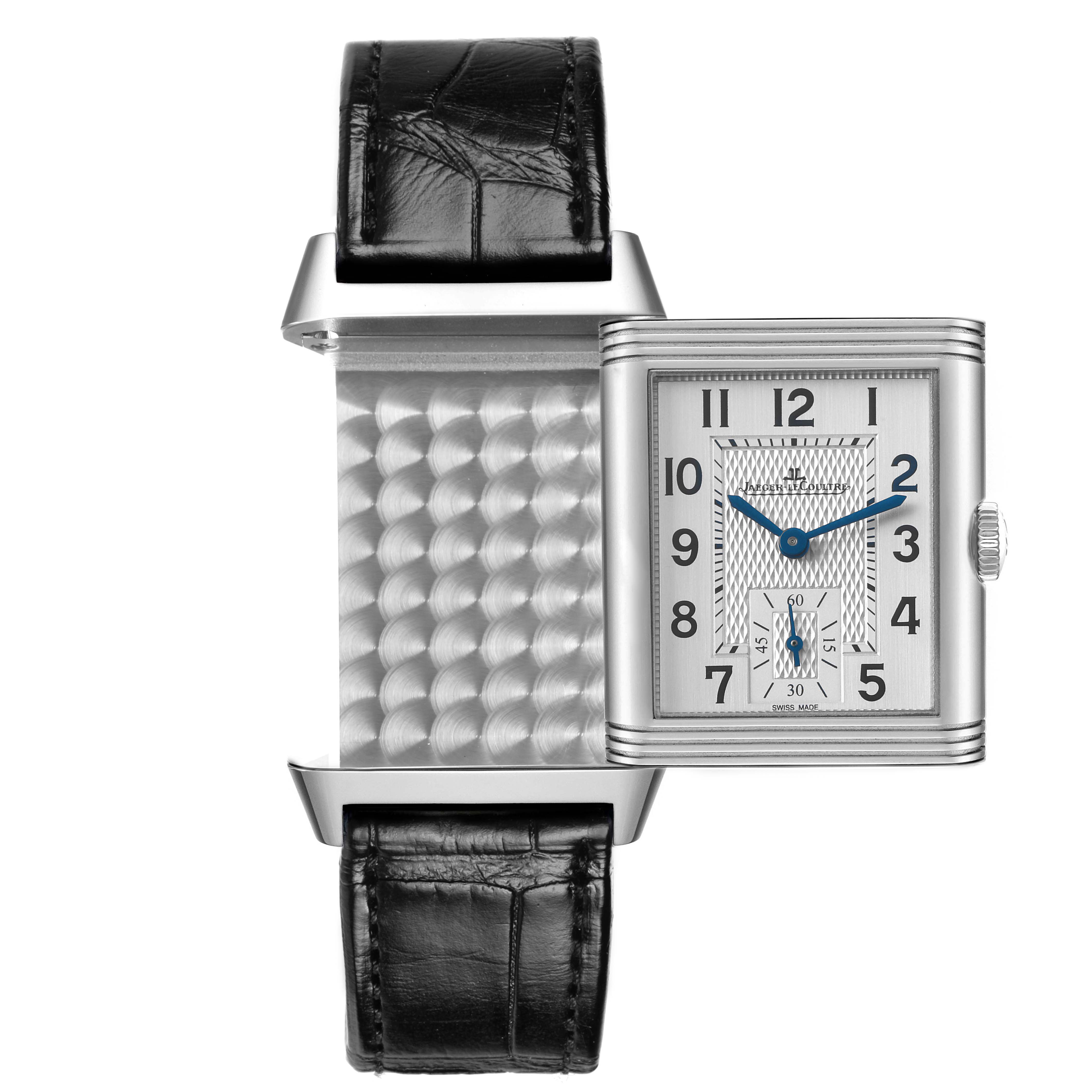The Jaeger-LeCoultre Reverso watch is shown from a front angle, displaying its reversible case and guilloché pattern.