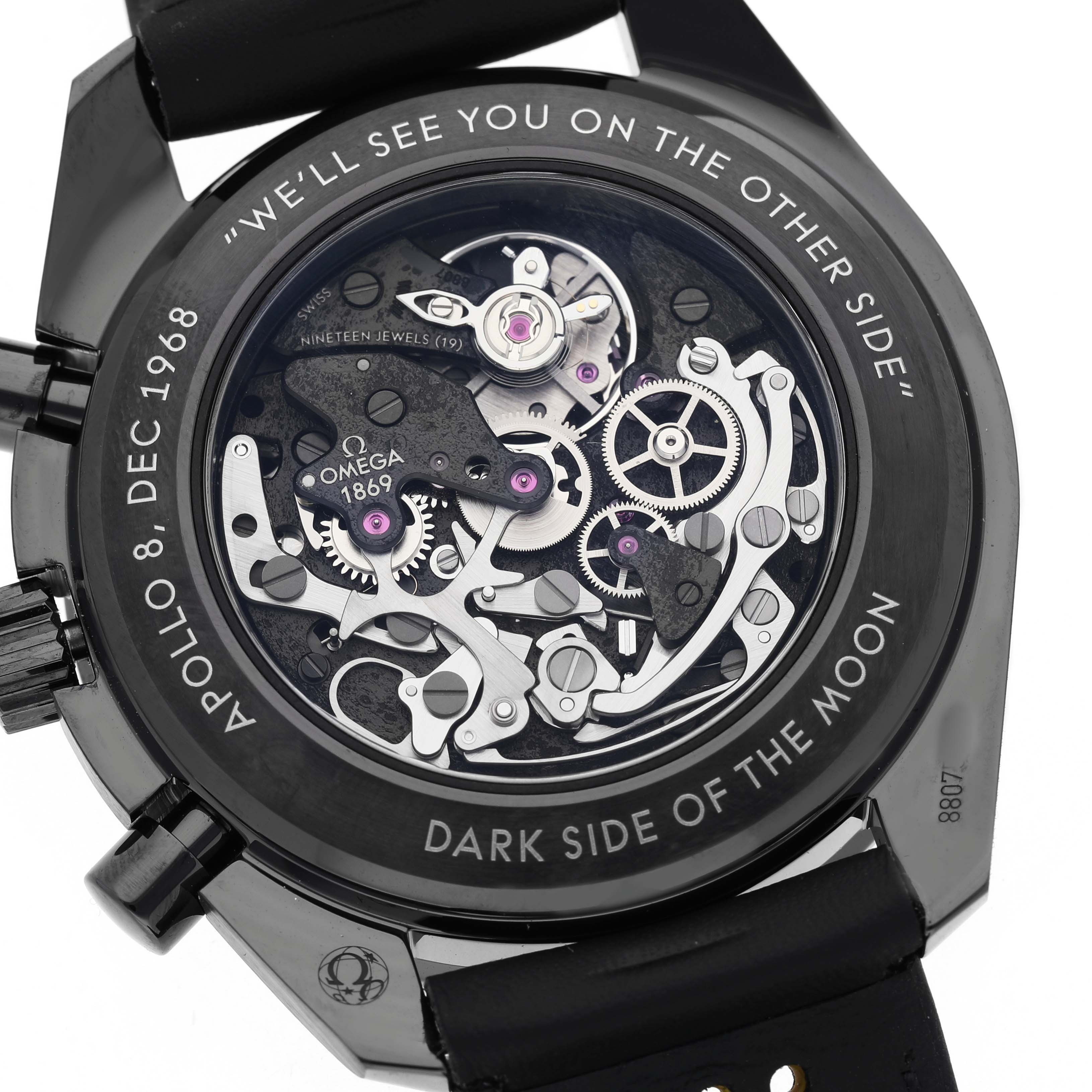 The image shows the back view of an Omega Speedmaster 311.92.44.30.01.001 Men's Ceramic Black Dial, highlighting its exposed movement and engraved details.