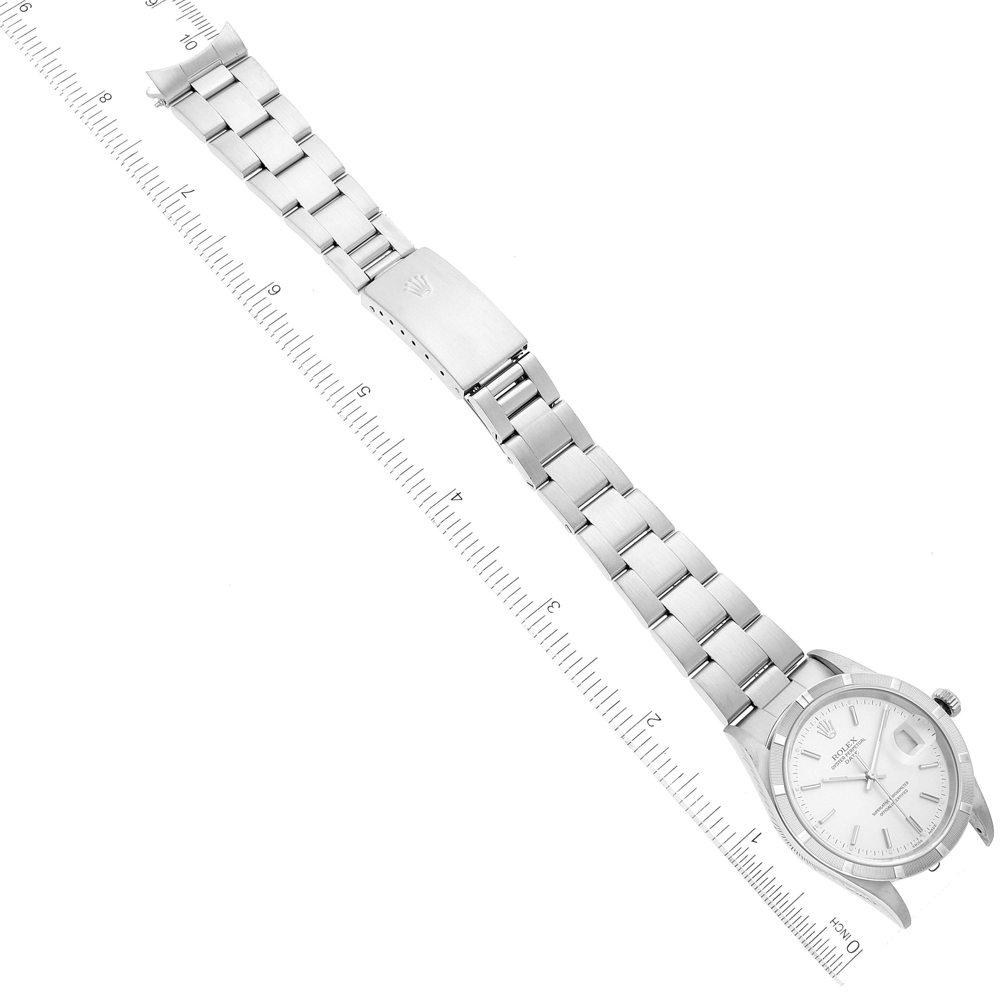 The image shows an overhead view of a Rolex Date 15210 Men
s Stainless Steel Silver Dial 15210 Men
s Stainless Steel Silver Dial model watch including the face, bracelet, and clasp, alongside a ruler for scale.